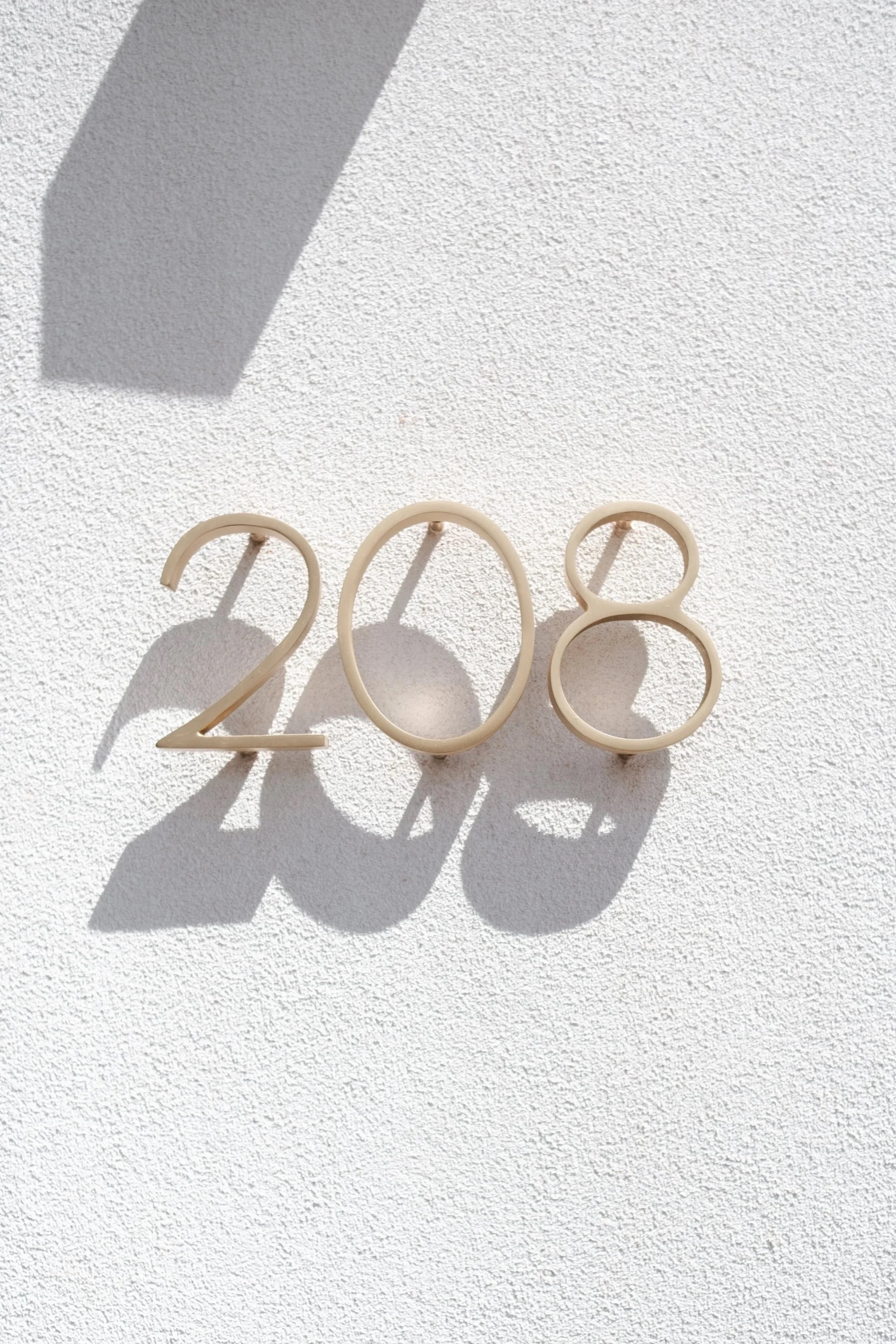 White numerical cutouts forming '2028' on a textured white wall with shadows.