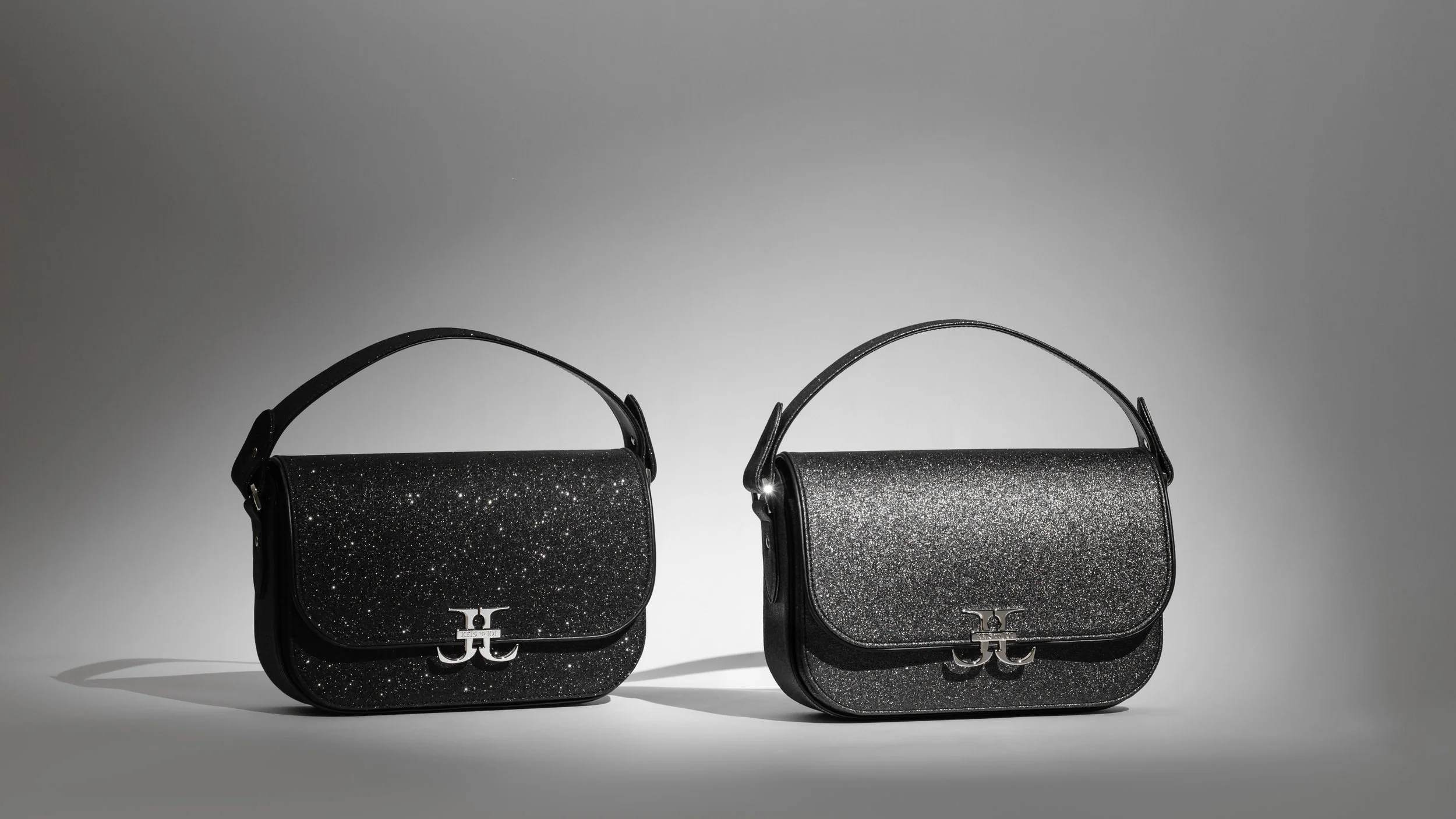 Two black glittery handbags with metallic logo clasps on a neutral background.