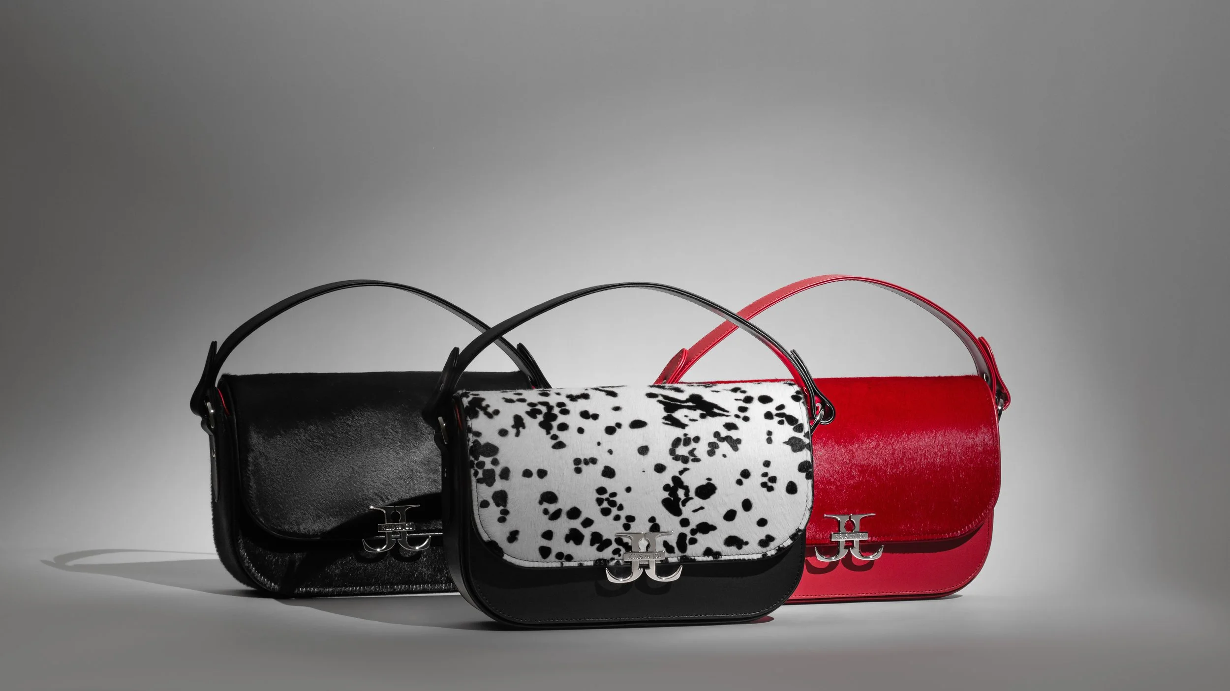 Three designer handbags in black, black and white, and red, displayed against a plain gray background.