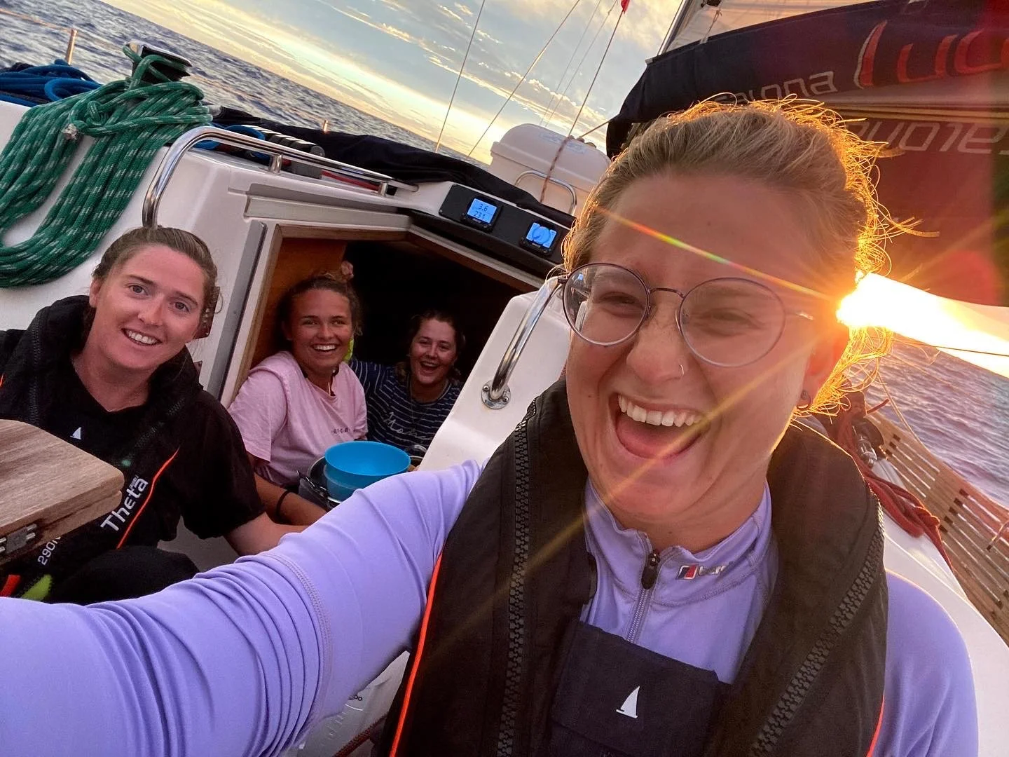 Group of friends smiling and enjoying a boat ride at sunset on the water.