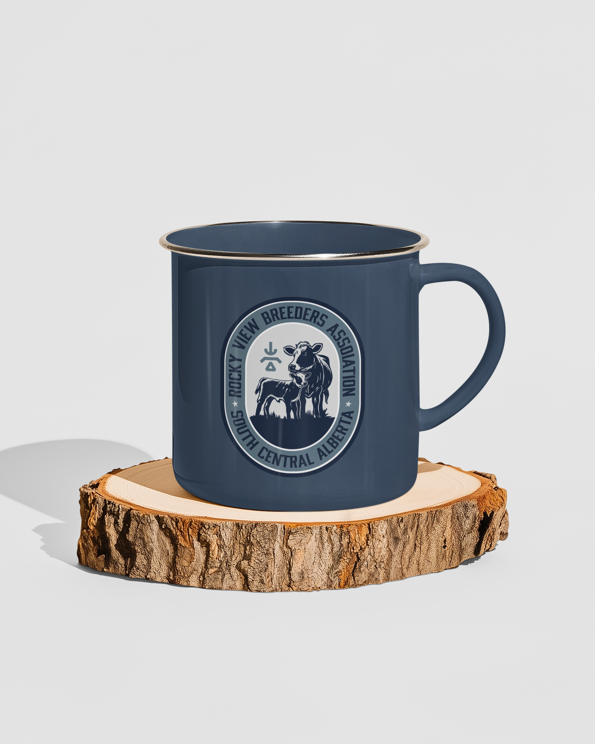 Blue enamel mug on a wooden slice with a logo of Rocky View Breeders Association, Central Alberta, featuring a cow and calf.