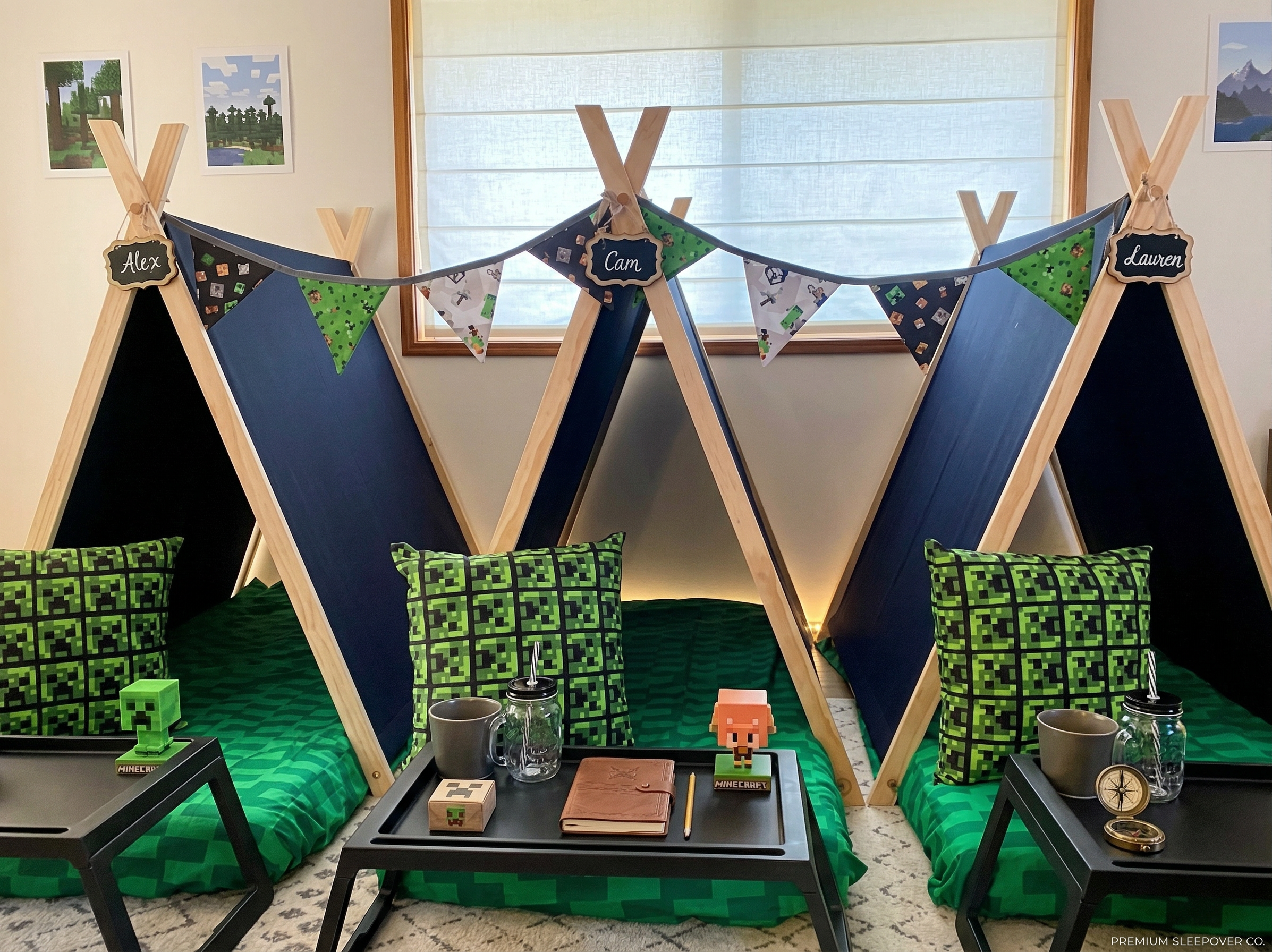Three teepees with Minecraft-themed bedding and pillows, decorated with bunting, each labelled with a child’s name, with a window in the background. A sleepover party setup.