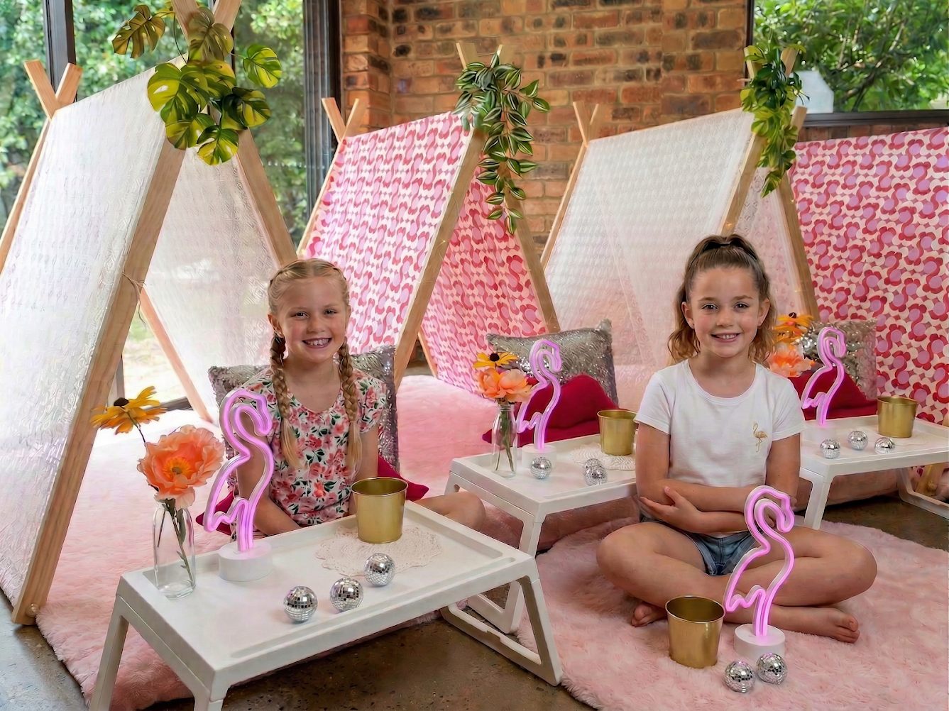 Two girls at a teepee sleepover party. Lace and patterned teepees with tray table and flamingo. A beautifully themed sleepover party for kids. 