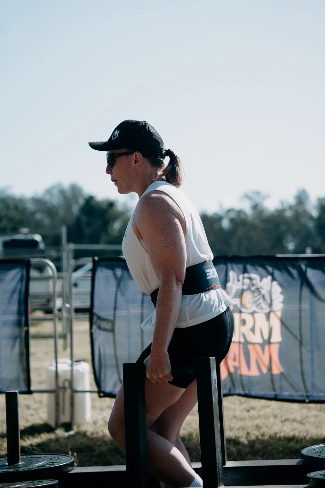 Farm Strong athlete lifting the carry frame in front of The Farm Jam banner, Tocal College