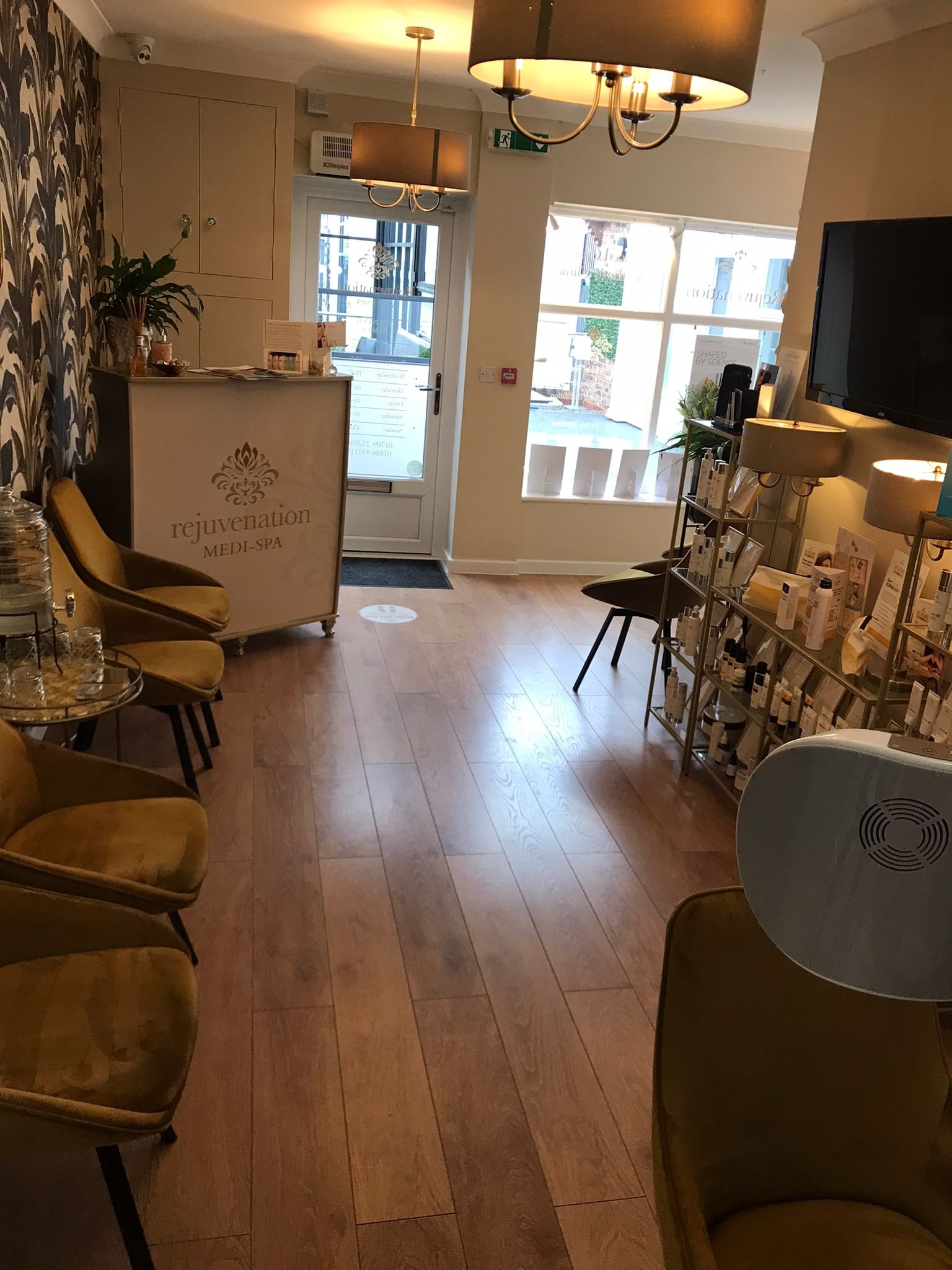 Interior of a spa or wellness salon with seating, product displays, and a reception desk that reads 'rejuvenation MEDI-SPA'.
