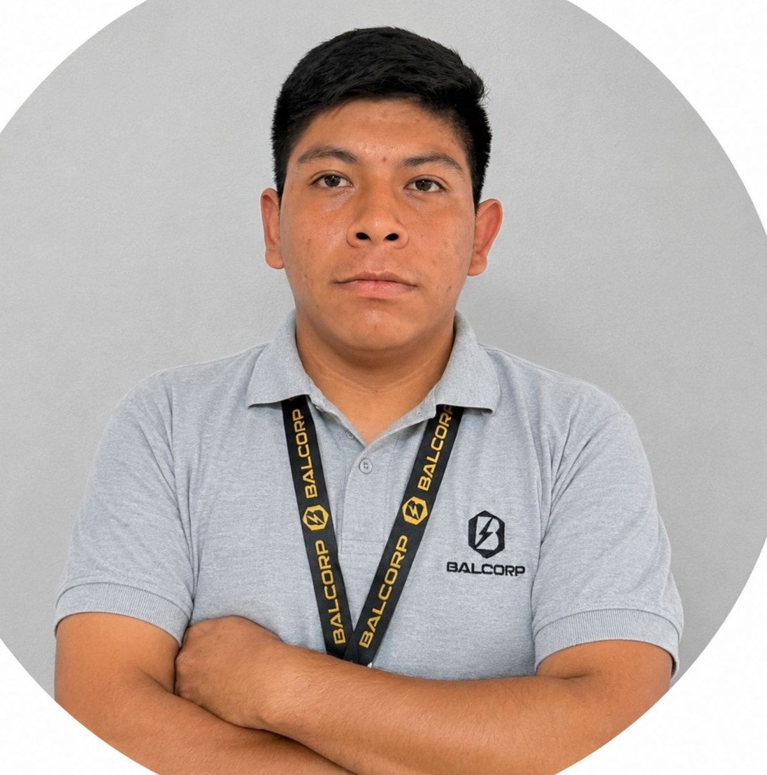 Hombre con camiseta gris y credencial colgada con logotipo de Balcorp, posa con los brazos cruzados frente a fondo gris.