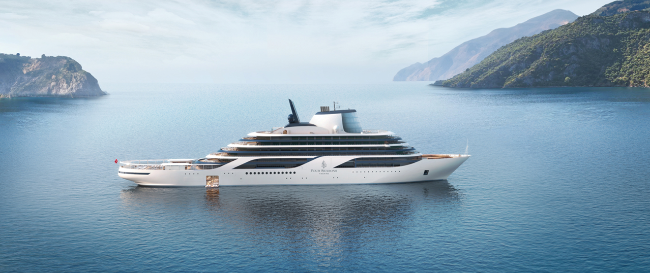 A sleek Four Seasons Yacht anchored in a scenic Mediterranean cove, representing intimate boutique nautical voyages.
