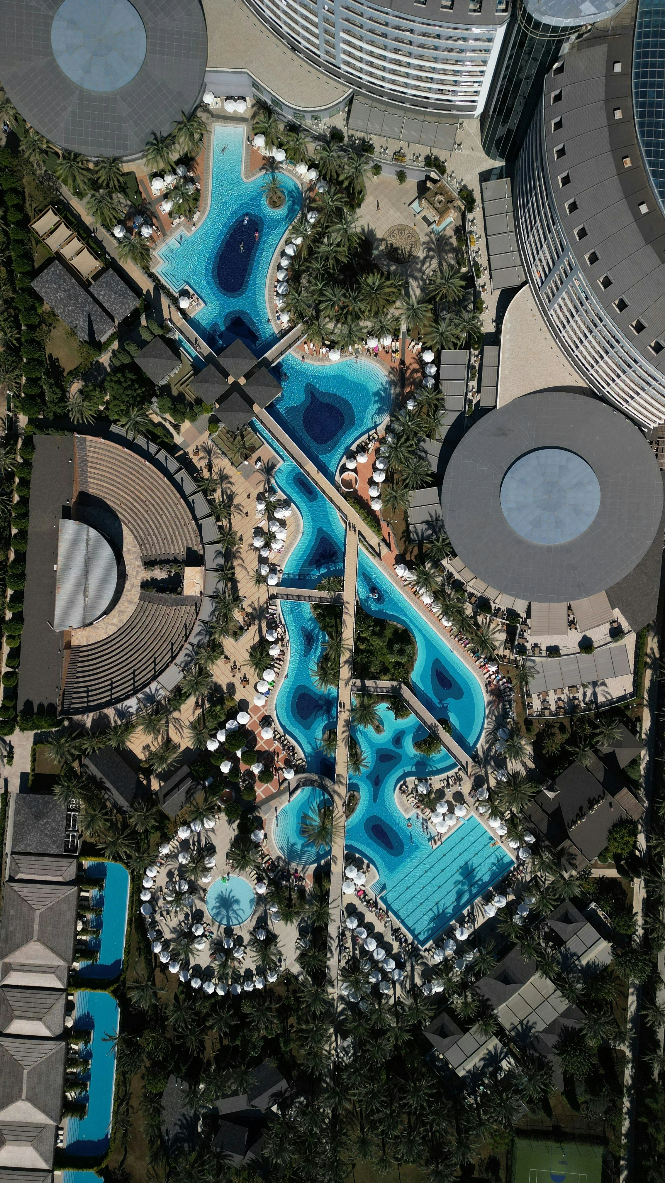 Aerial view of a luxury all-inclusive resort featuring expansive turquoise swimming pools and palm trees, showcasing premium vacation packages curated by The Unpunctual.