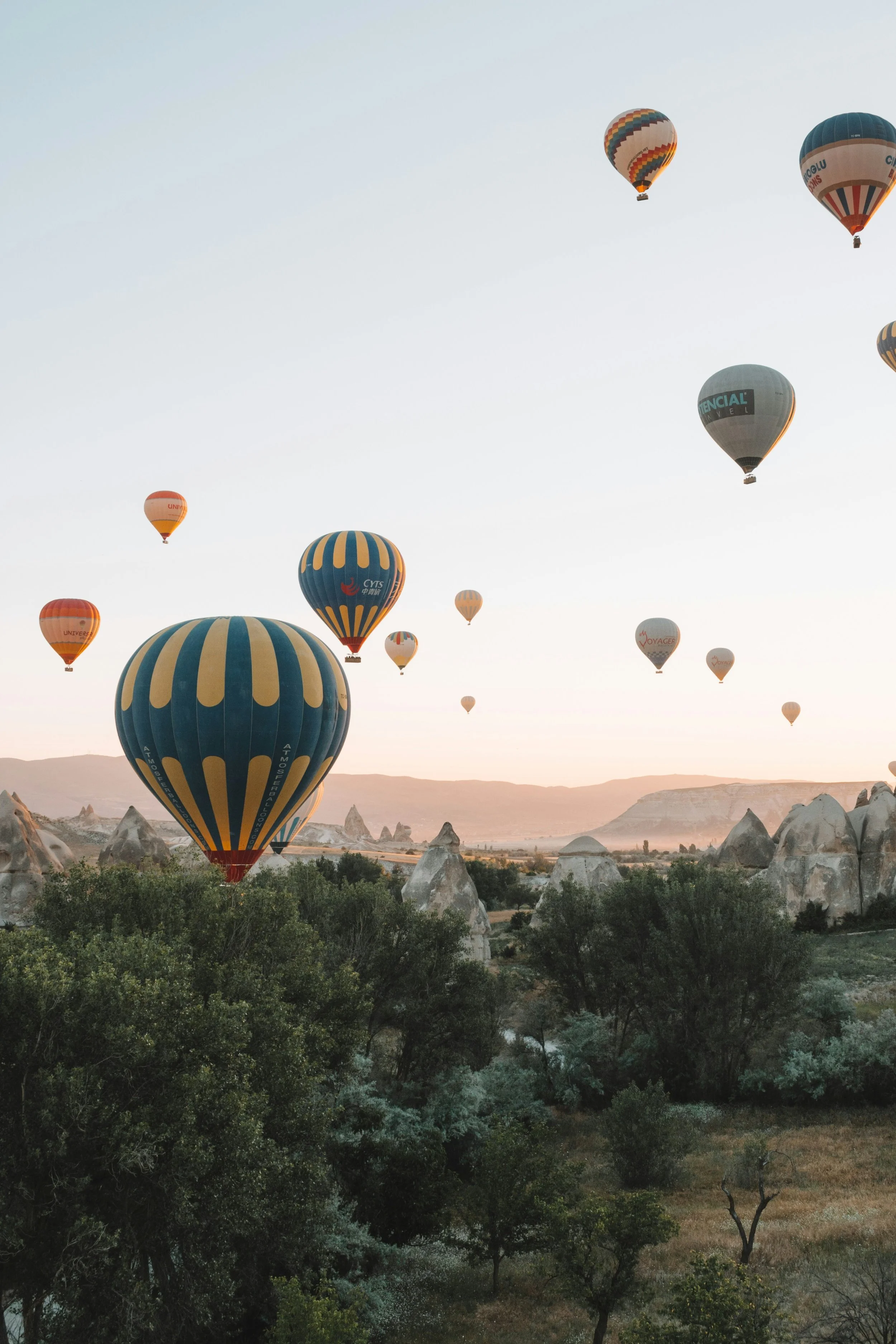 Colorful hot air balloons floating over the fairy chimneys of Cappadocia, Turkey, representing customizable international travel itineraries and luxury expeditions by The Unpunctual.