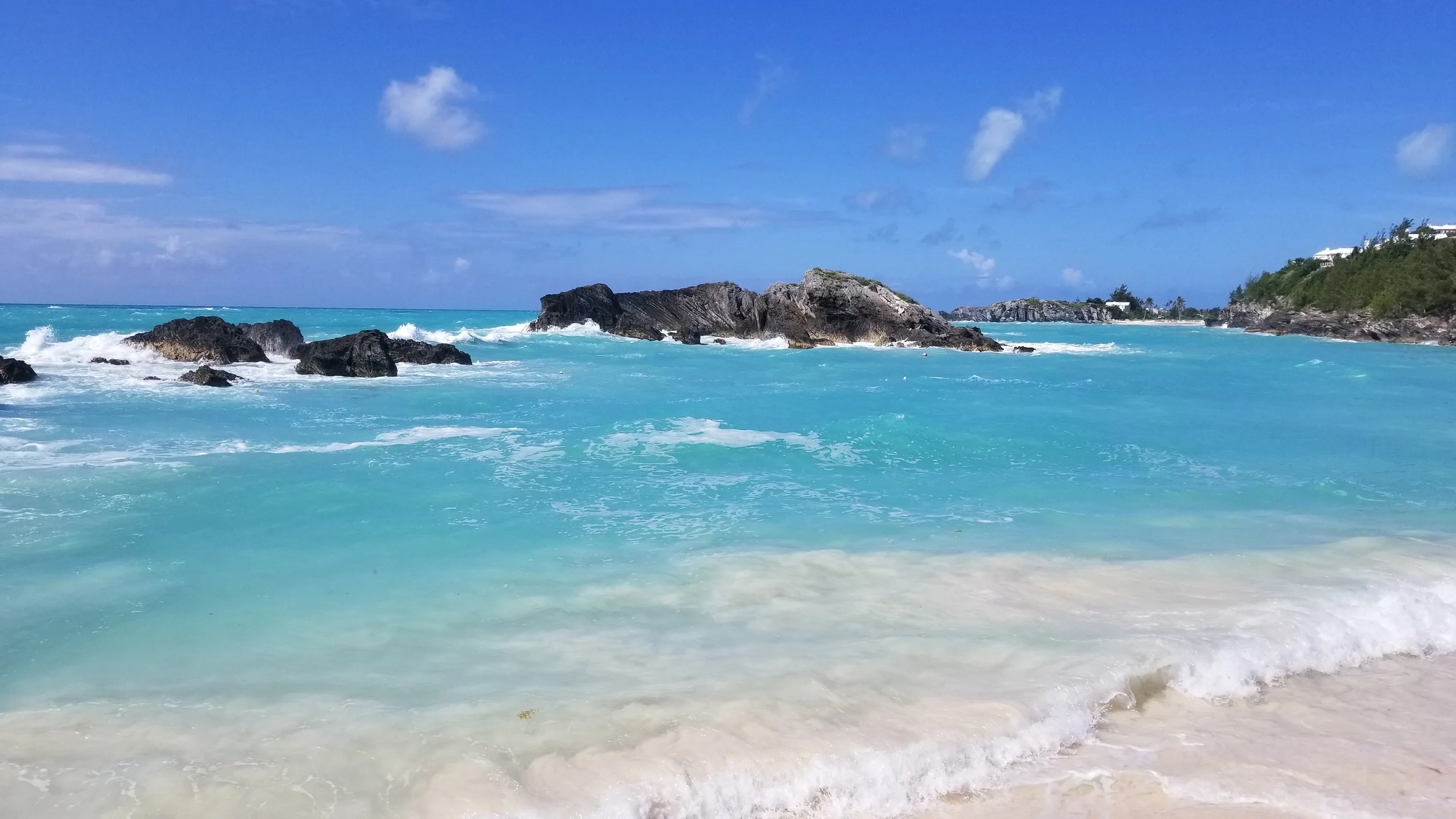 Turquoise ocean waves crashing against rocky coves at a Bermuda pink beach, showcasing curated island itineraries and seamless tropical vacation planning
