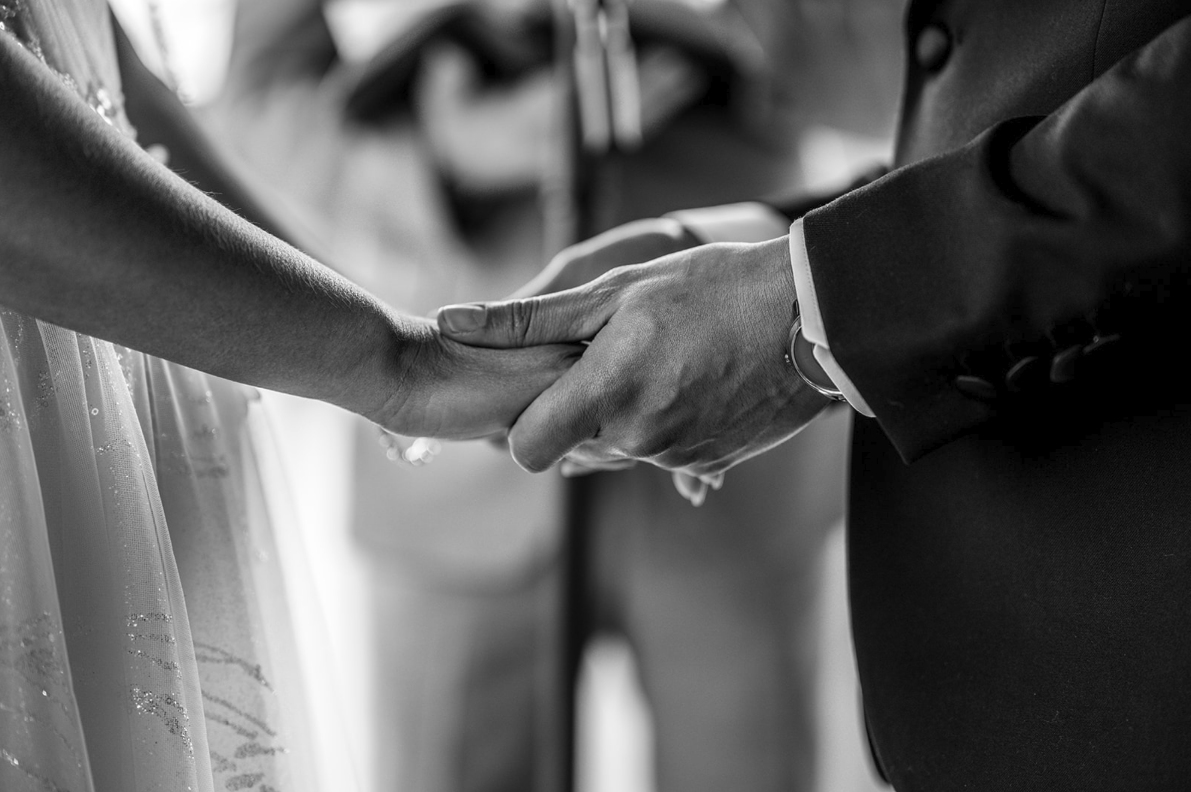 Close-up of a bride and groom holding hands during their wedding ceremony.