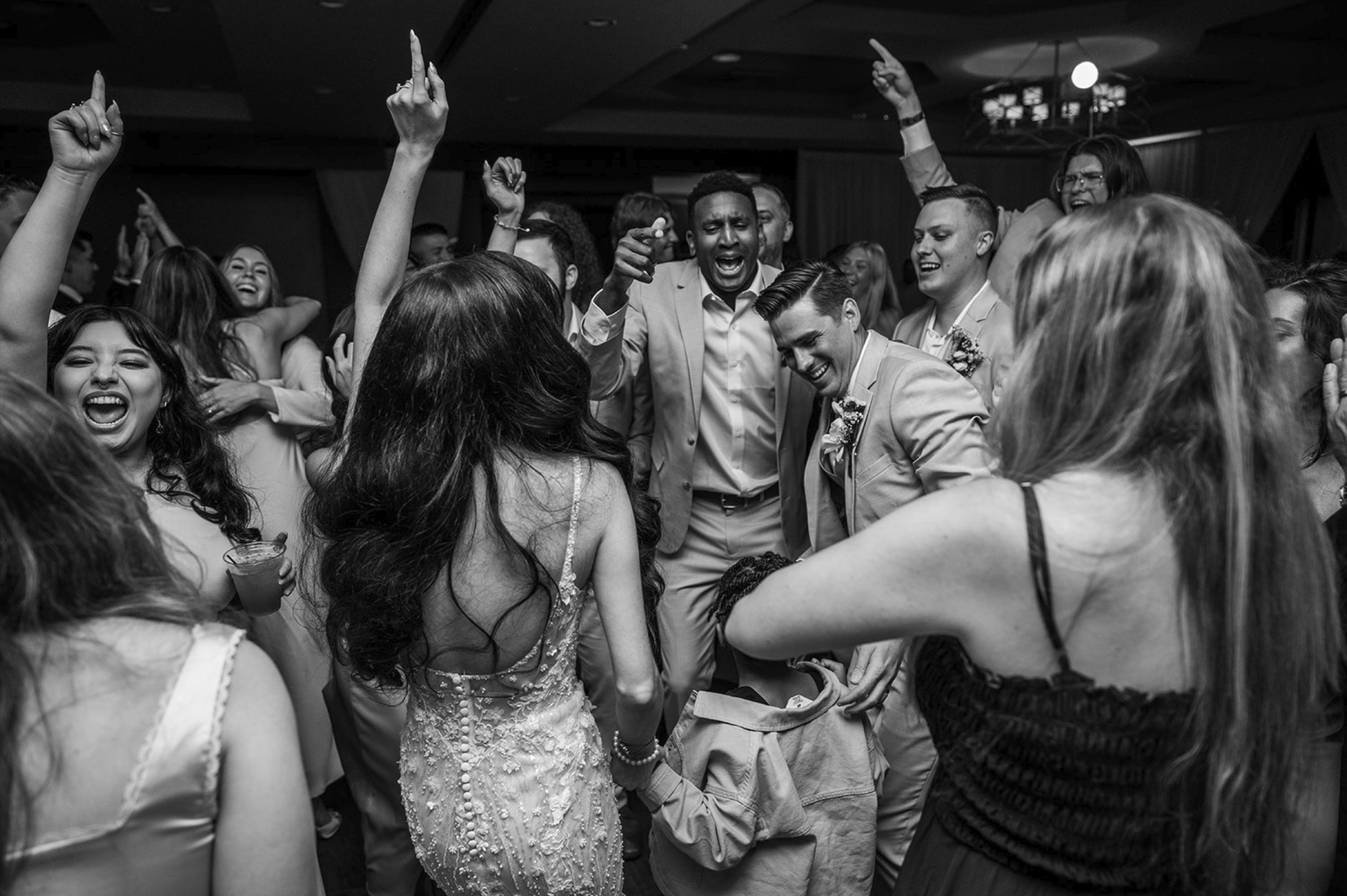 People dancing and celebrating at a wedding reception in a crowded room, smiling and raising their hands. Wedgewood wedding venue Chino Hills.