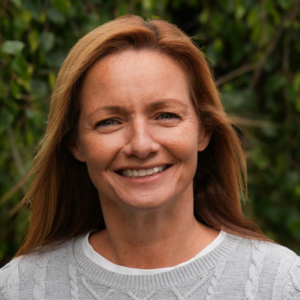 Headshot of Laura Livesey of WeeBit Digital taken outdoors in front of green foliage.
