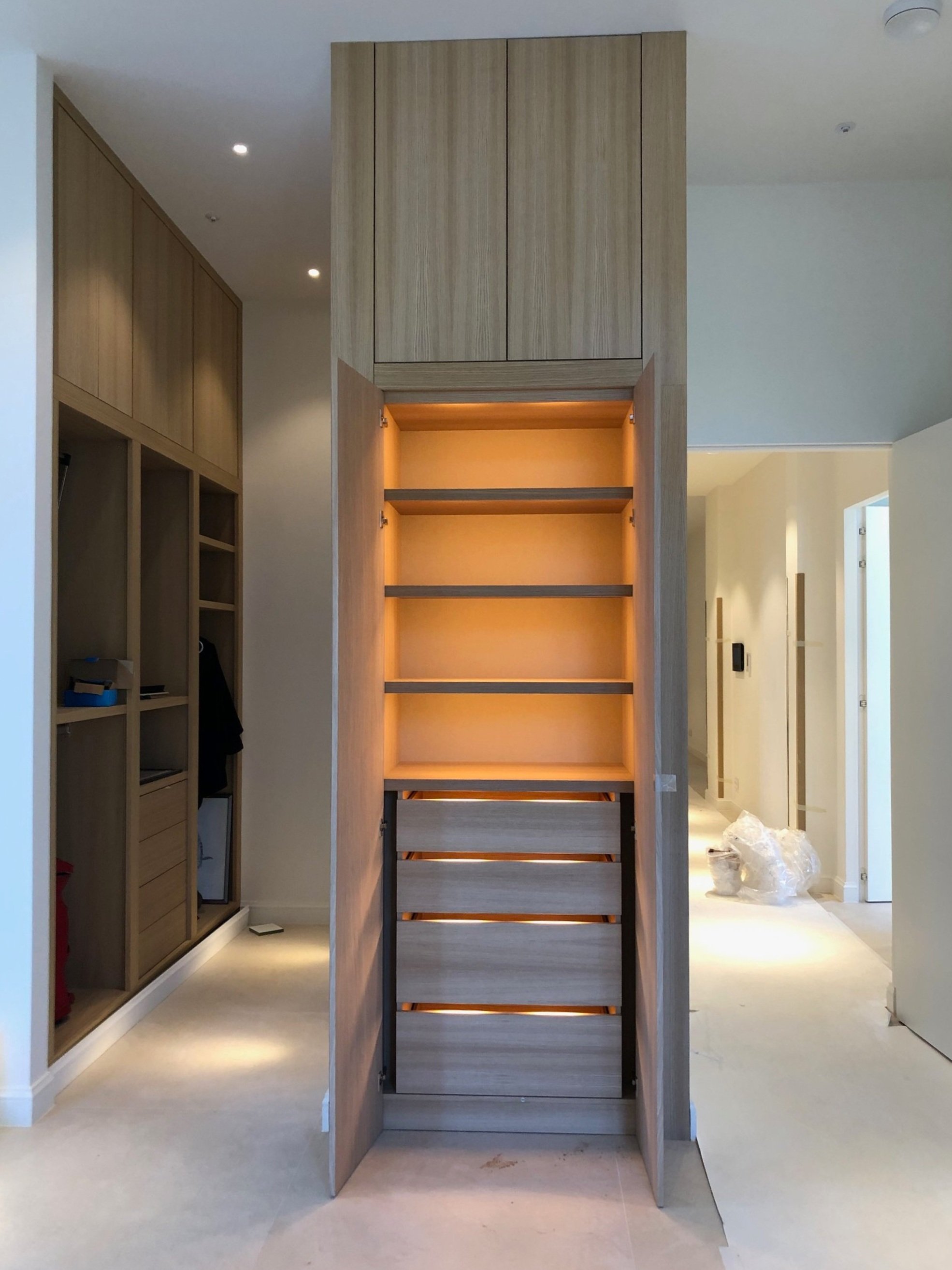 Gemonteerde houten kast met open gebogen deuren en ingebouwde verlichting in een modern interieur.
