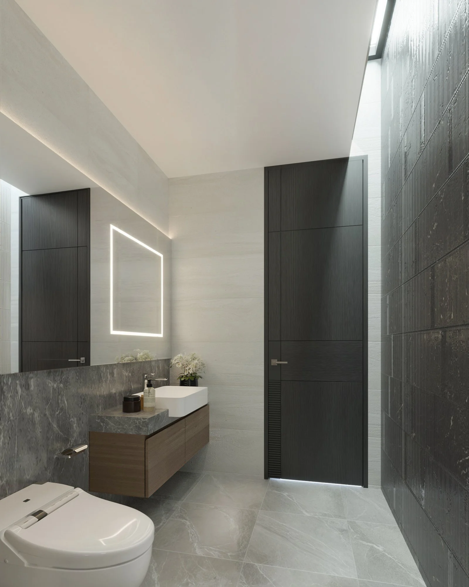 Statement bathroom with dark stone accent wall and illuminated vanity mirror.