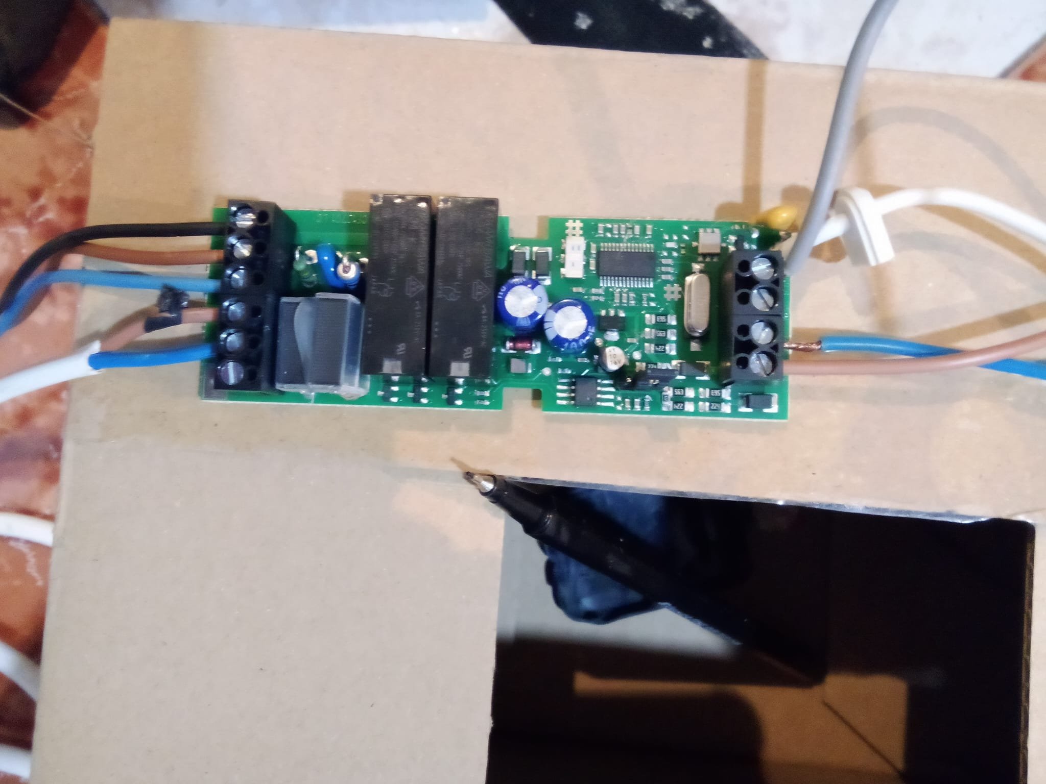 Una placa de circuito impreso con componentes electrónicos, cables conectados en los extremos y una caja negra debajo.