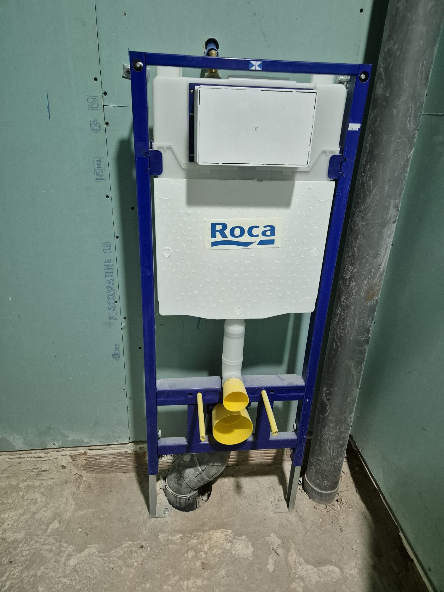 Sistema de inodoro empotrado con cisterna marca Roca, instalado en muro en construcción.