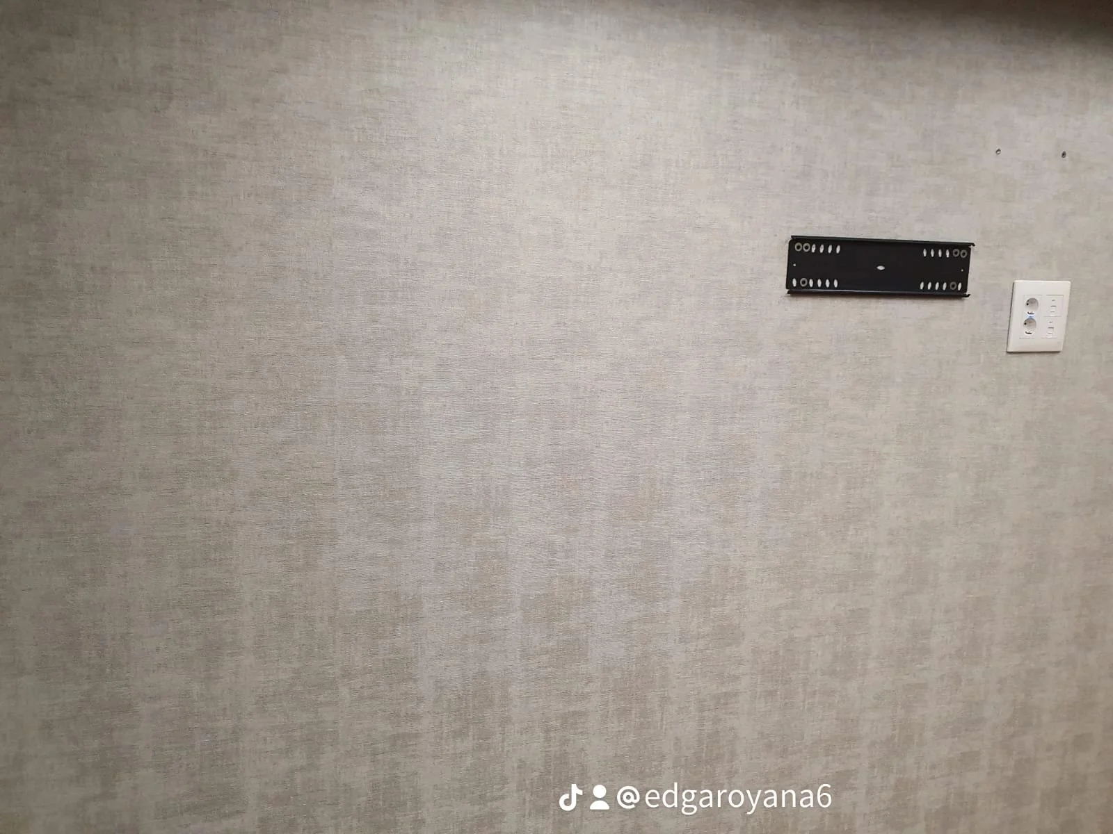 Pared con una placa de soporte de tubo de vídeo y un enchufe eléctrico.