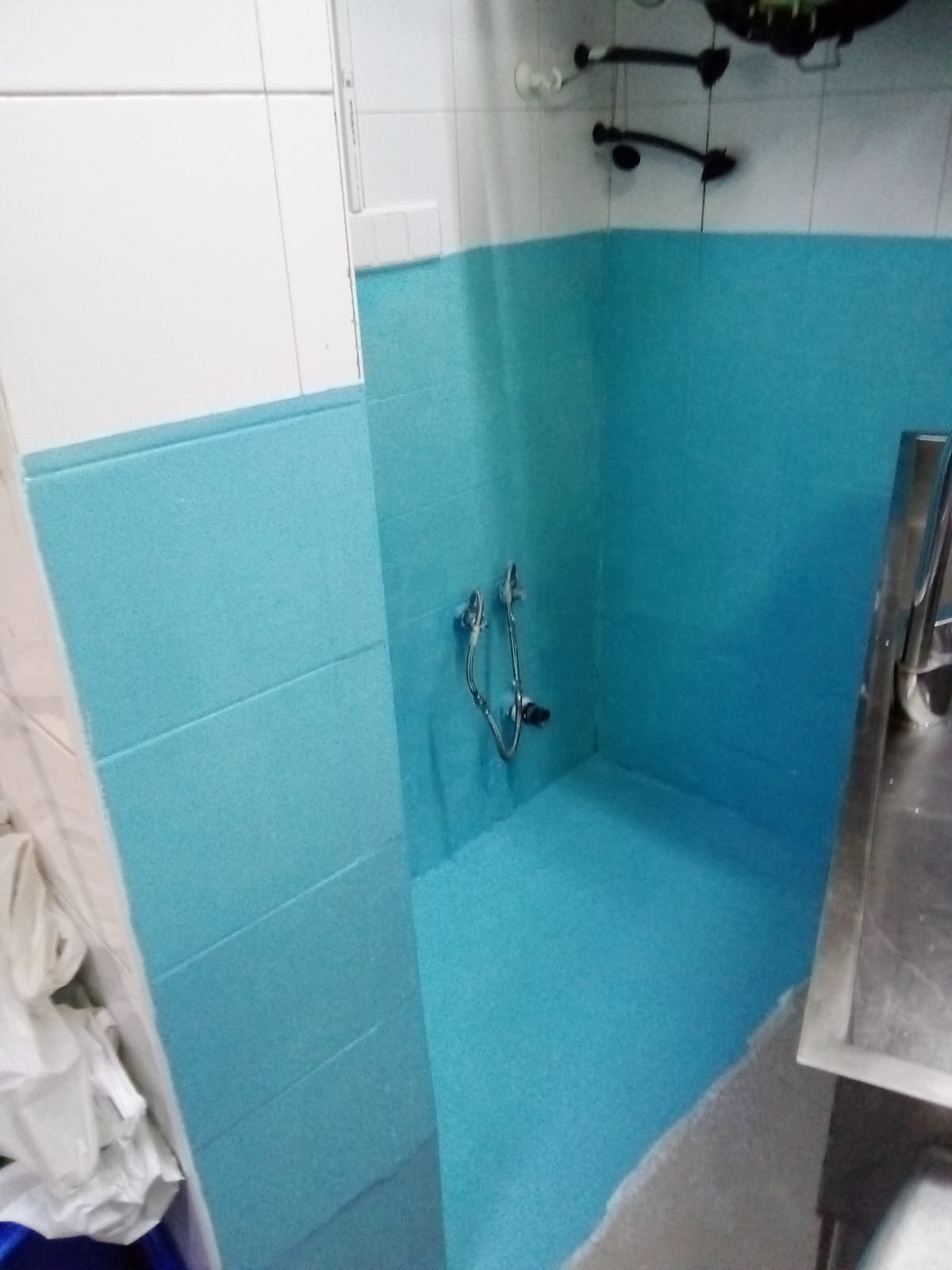 Lavabo en construcción con paredes parcialmente azules y tuberías expuestas.