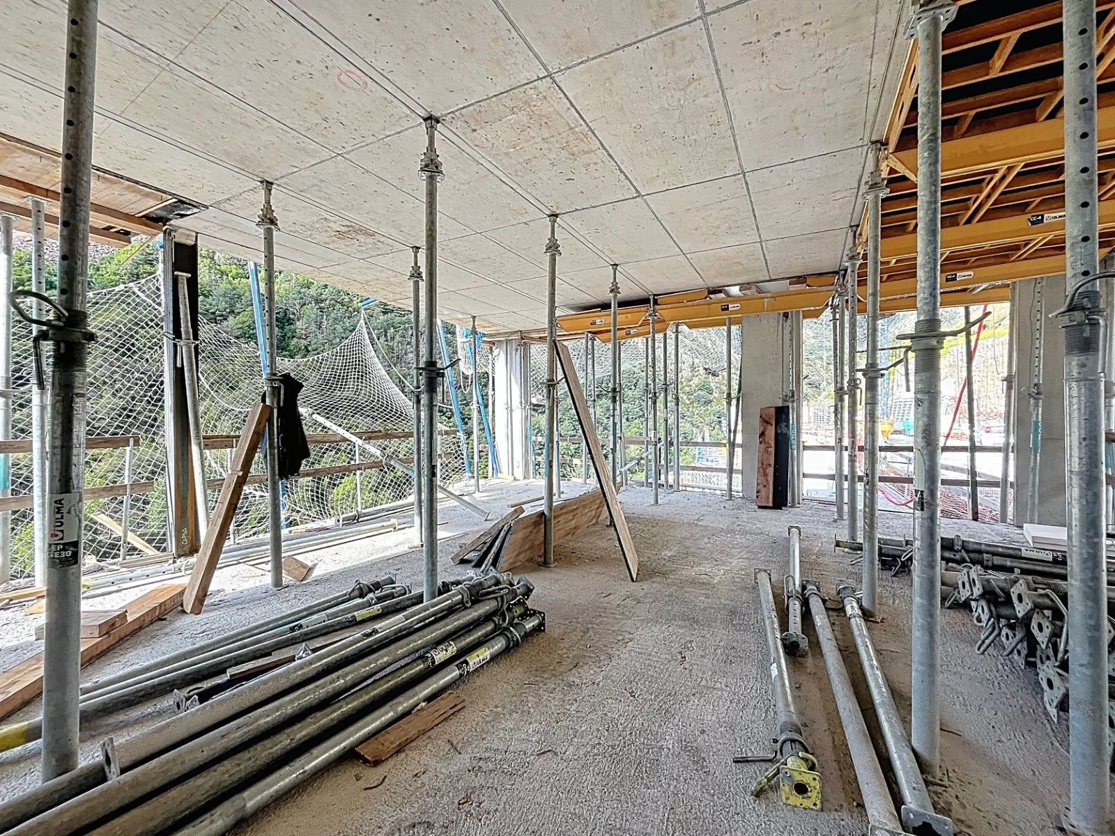 Interior de un edificio en construcción con estructuras de andamios y viguetas de concreto.