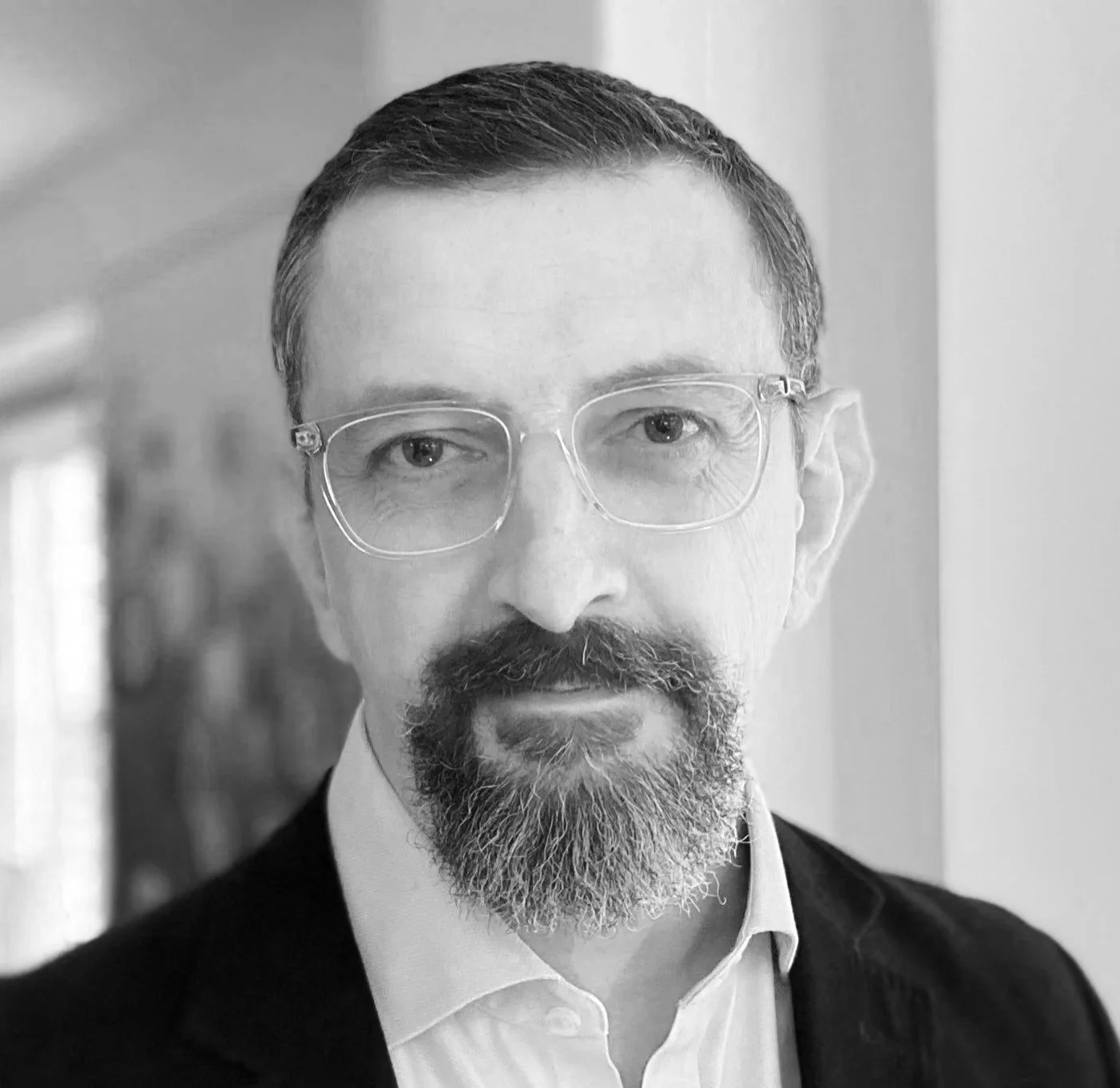 Professor Nick Kemsley, Black-and-white portrait of a man with glasses, a beard, and a mustache, wearing a suit and white shirt, indoors.