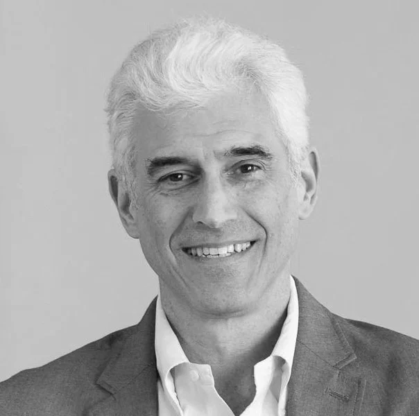 Black and white photo of a smiling man with gray hair wearing a suit and white shirt.