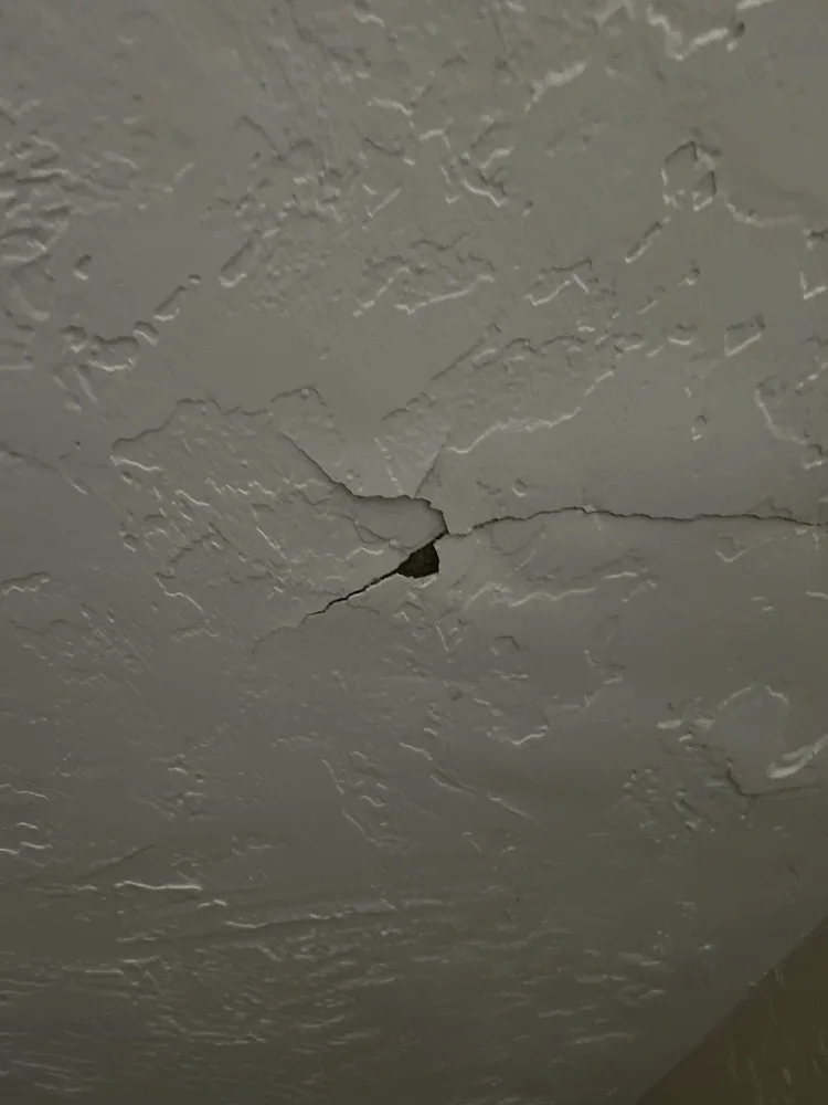 Before repair: cracked and punctured textured drywall.