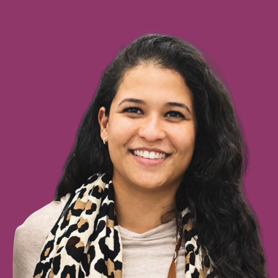 A young woman with long dark hair smiling against a pink background.