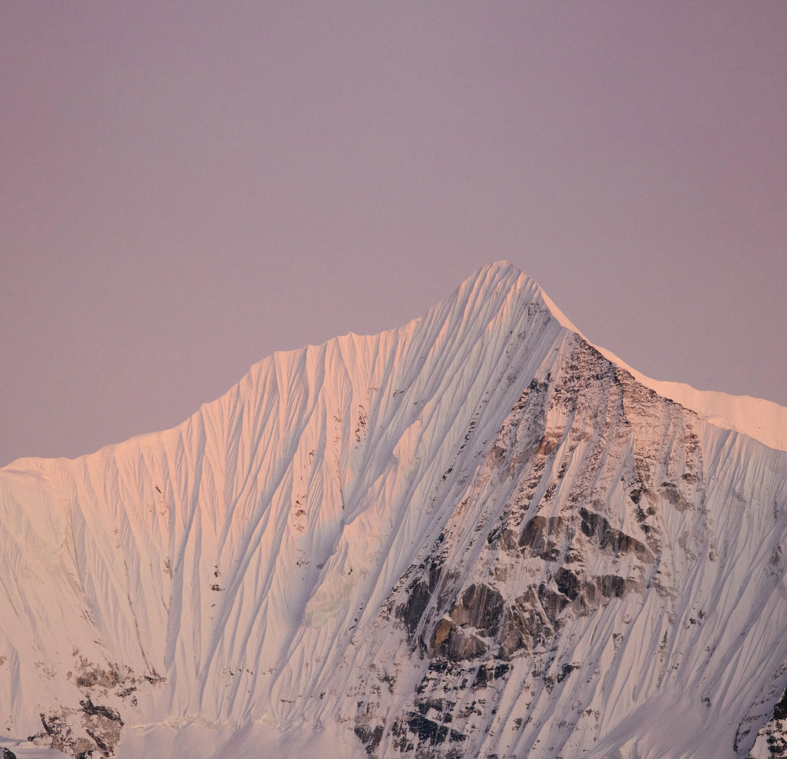 Schneebedeuter Berg mit markanten Gipfel bei Sonnenaufgang oder Sonnenuntergang, sanfter Himmel