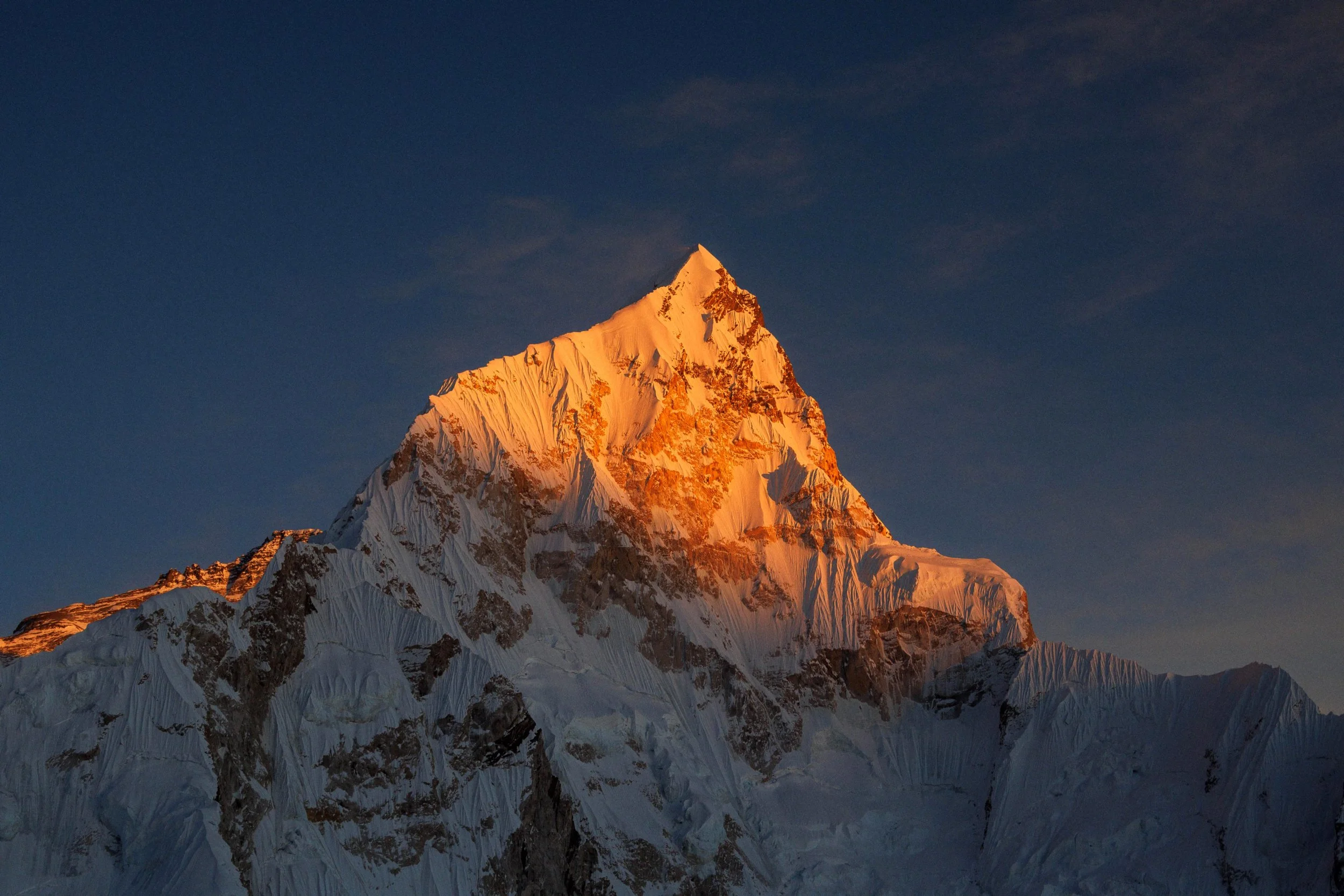 Berggipfel bei Sonnenuntergang mit schneebedeckten Flächen und einem klaren blauen Himmel. Gruppenreise mit Sonnenaufgängen und Untergängen um den Himalaya ganz besonders zu erleben. Abenteuer und Fotografie Workshop mit Aspire Adventures.