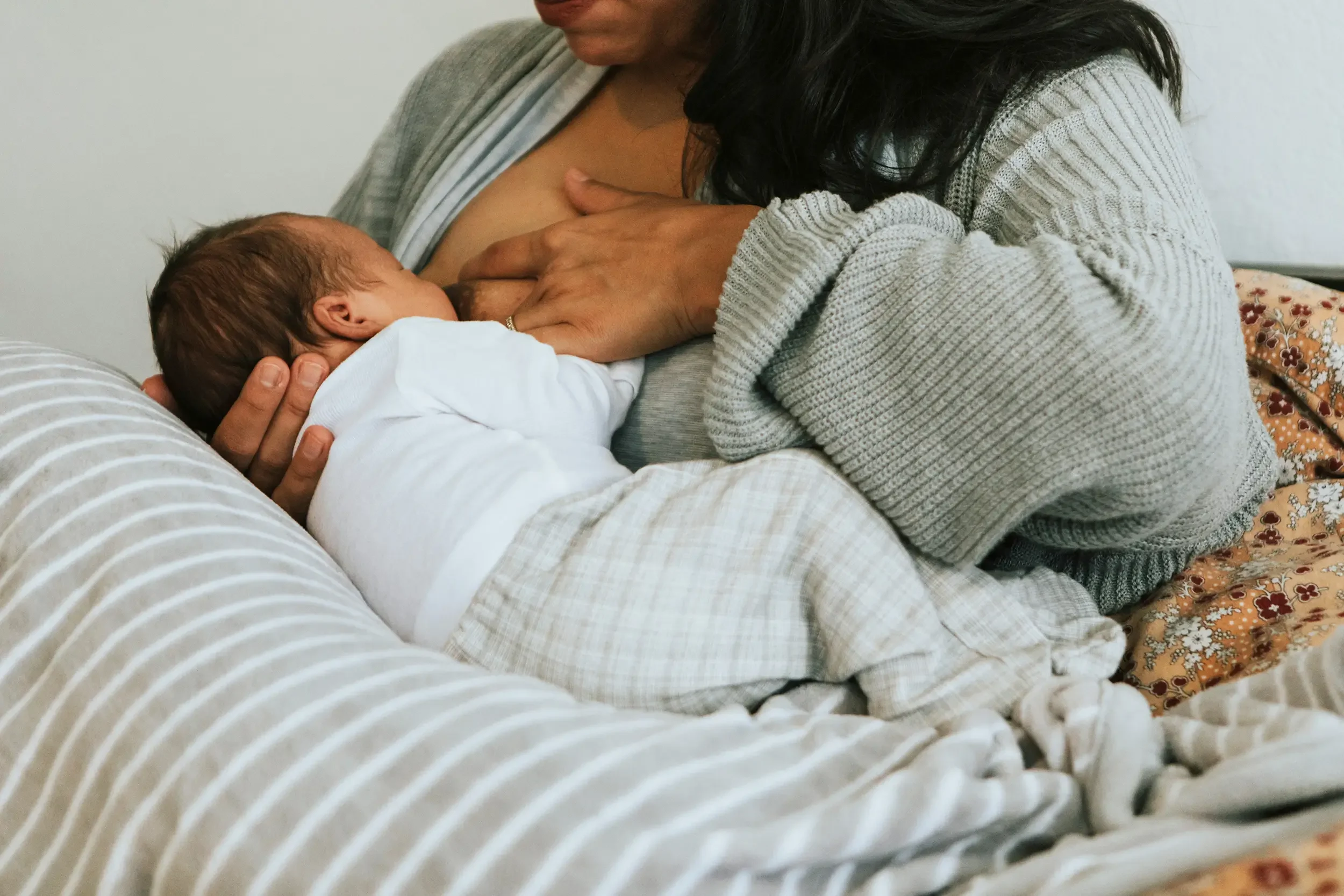 Mom breastfeeding infant on pillow after lip tie revision and chiropractic support for feeding.