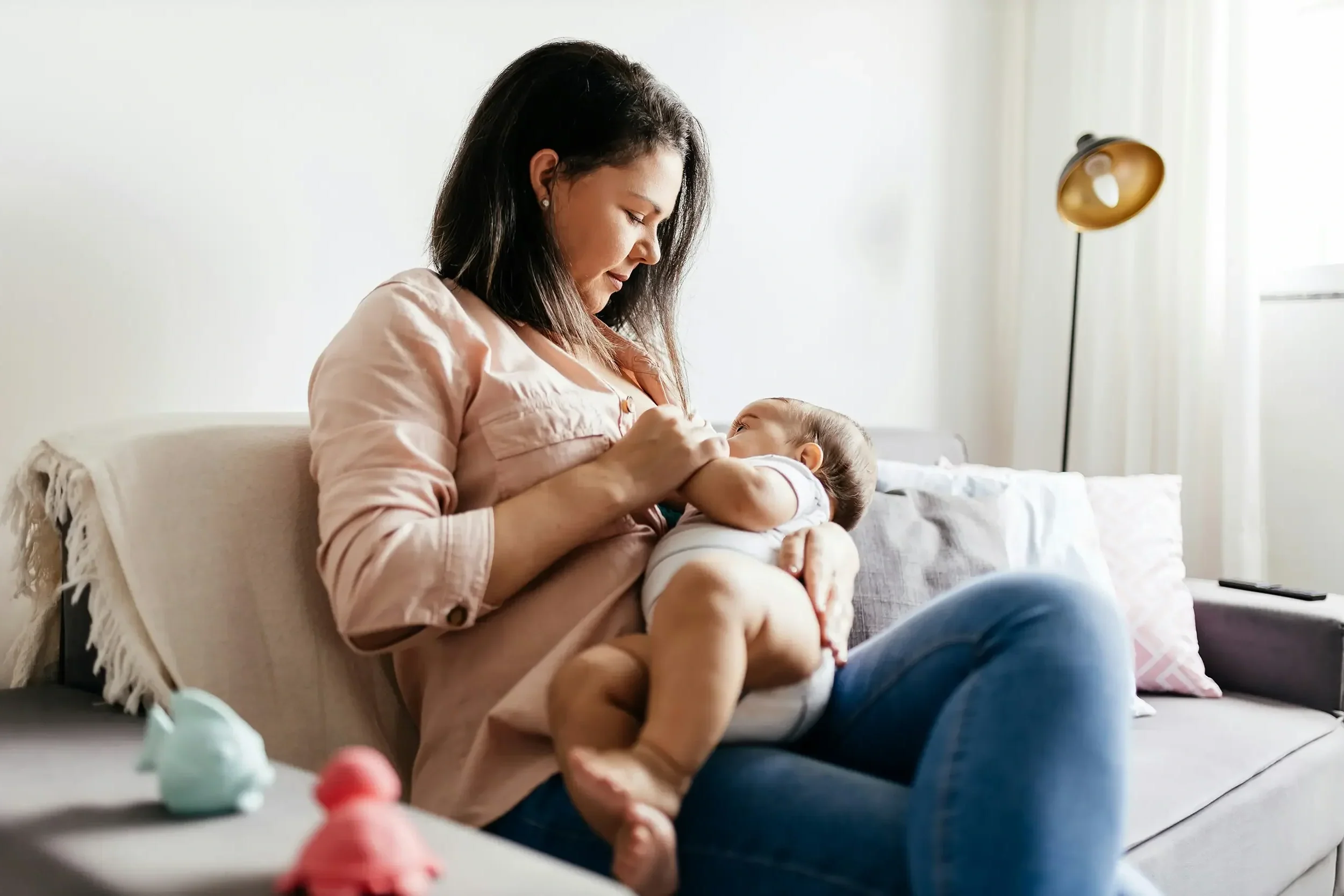 Mom breastfeeding baby on couch after tongue tie revision and chiropractic support in Sioux Falls.