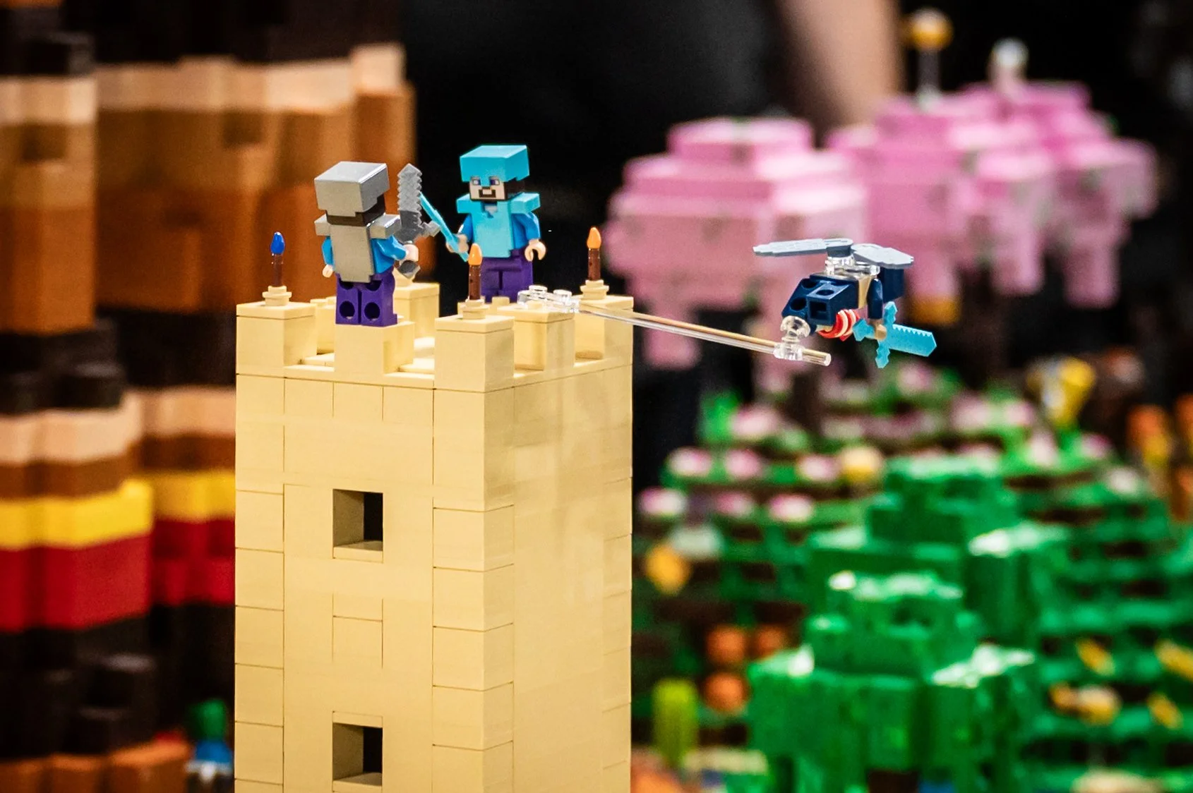 Eine LEGO-Szene mit zwei Minifiguren auf einer Burgmauer, die eine Rakete fliegen lassen, vor bunten LEGO-Bäumen.