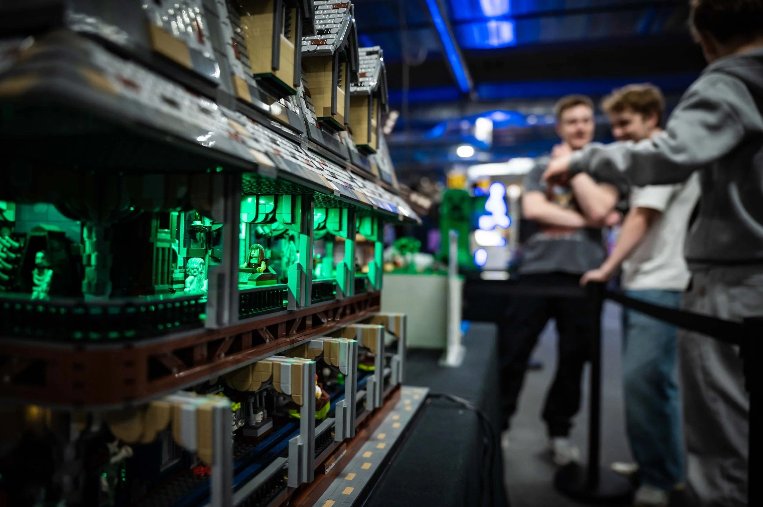 Lego-Szene mit grünen Lichteffekten und Menschen im Hintergrund auf einer Messe oder Ausstellung.