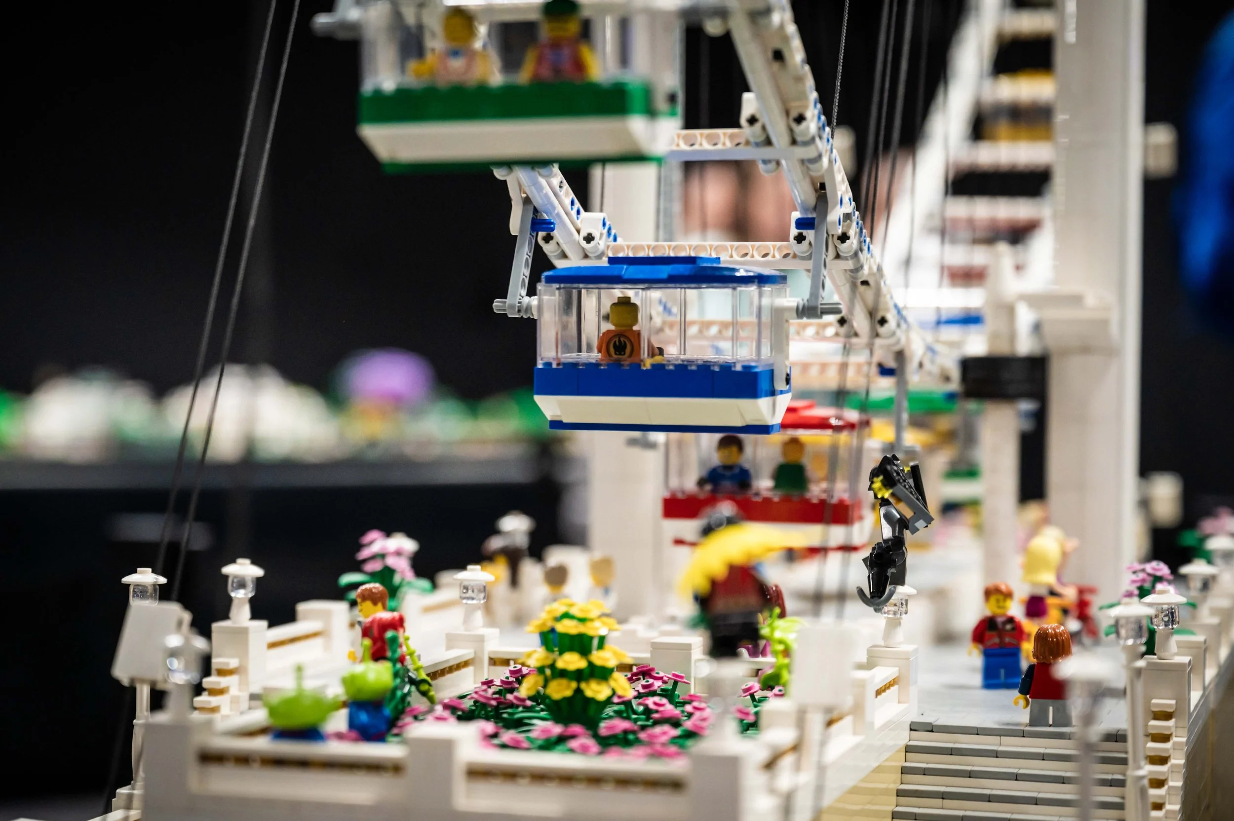 Eine LEGO-Freizeitparkattraktion mit einer verzierten Plattform, Blumenstrauß und Menschen, die in einer Gondelbahn unterwegs sind