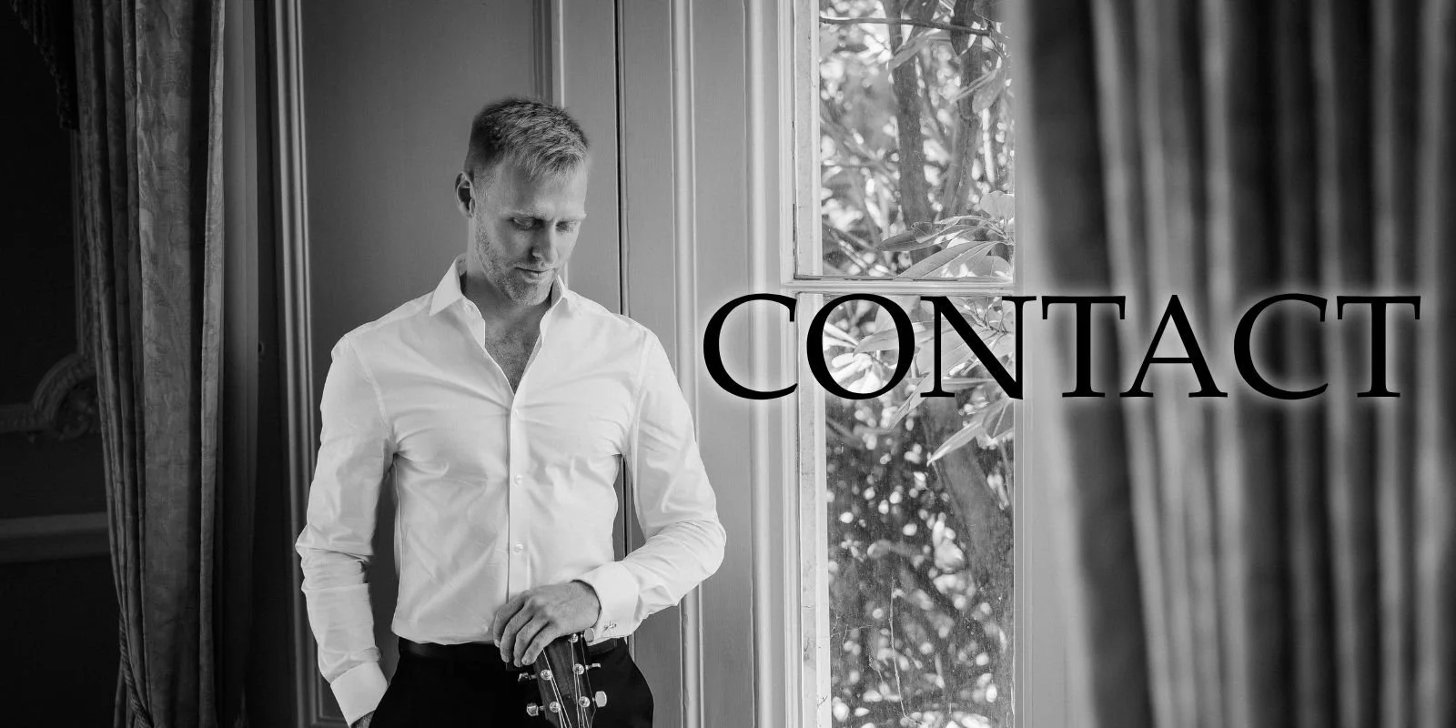 A man in a white dress shirt standing next to a window, with the word 'CONTACT' overlaid on the image.