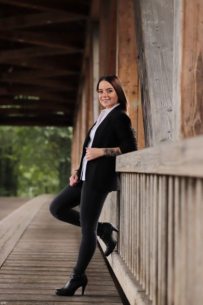 A woman stands on the wooden bridge and poses for a photo.