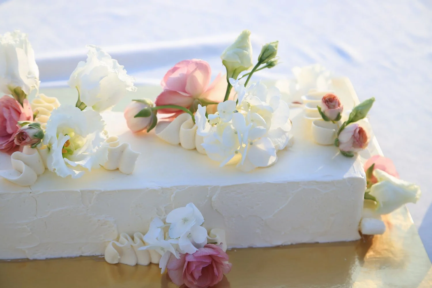 Die Hochzeitstorte mit rosa und weißen Blumen dekoriert.