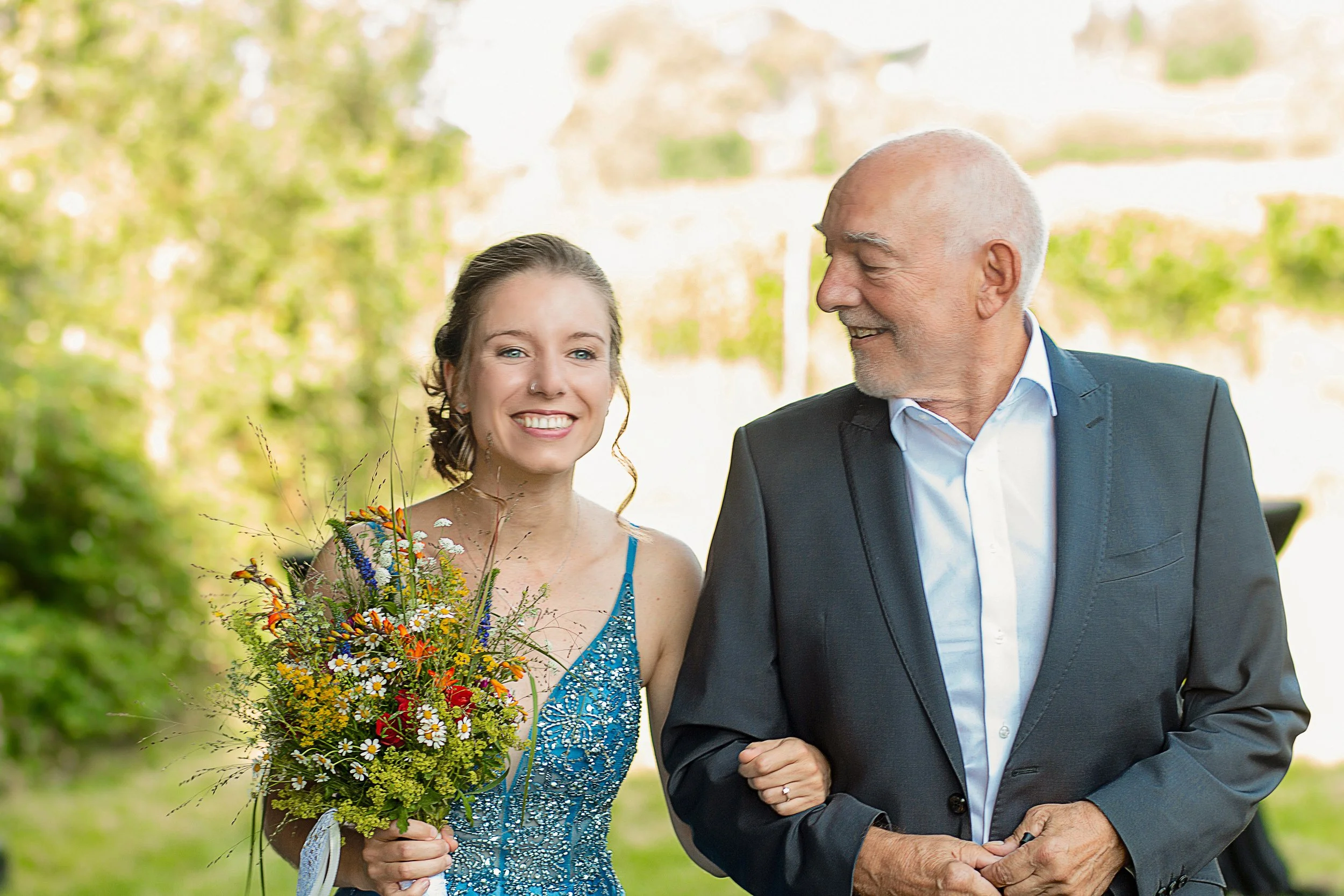 Die Braut und der Vater der Braut gehen gemeinsam spazieren, lächeln und genießen die Zeit miteinander.