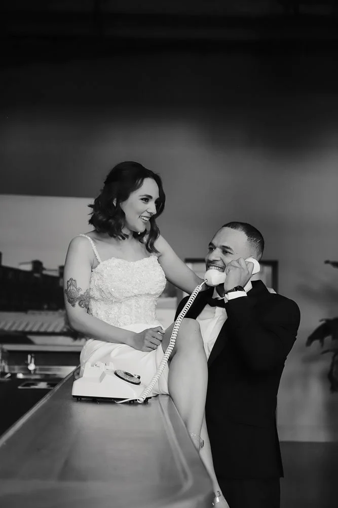 Das Brautpaar sitzt an einer Bar, umgeben von festlicher Dekoration, und strahlt vor Glück