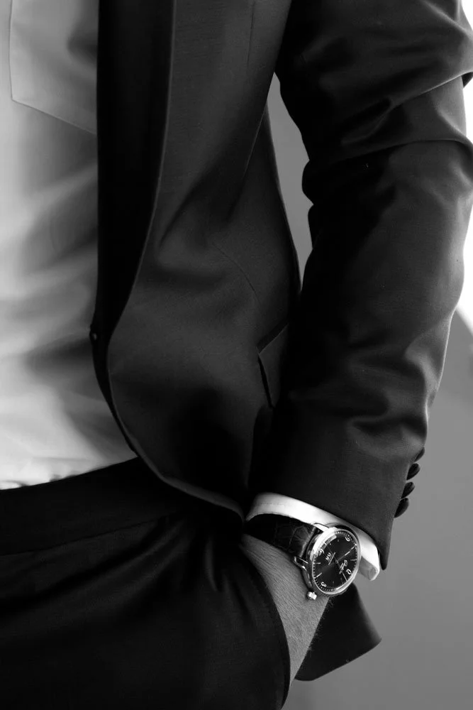 Bräutigam im Anzug und mit Krawatte trägt eine elegante Uhr an seinem Handgelenk.