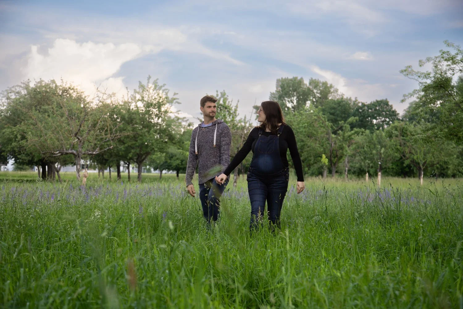 Frau und Mann laufen im Feld beim Babybauch Fotoshooting Heidelberg