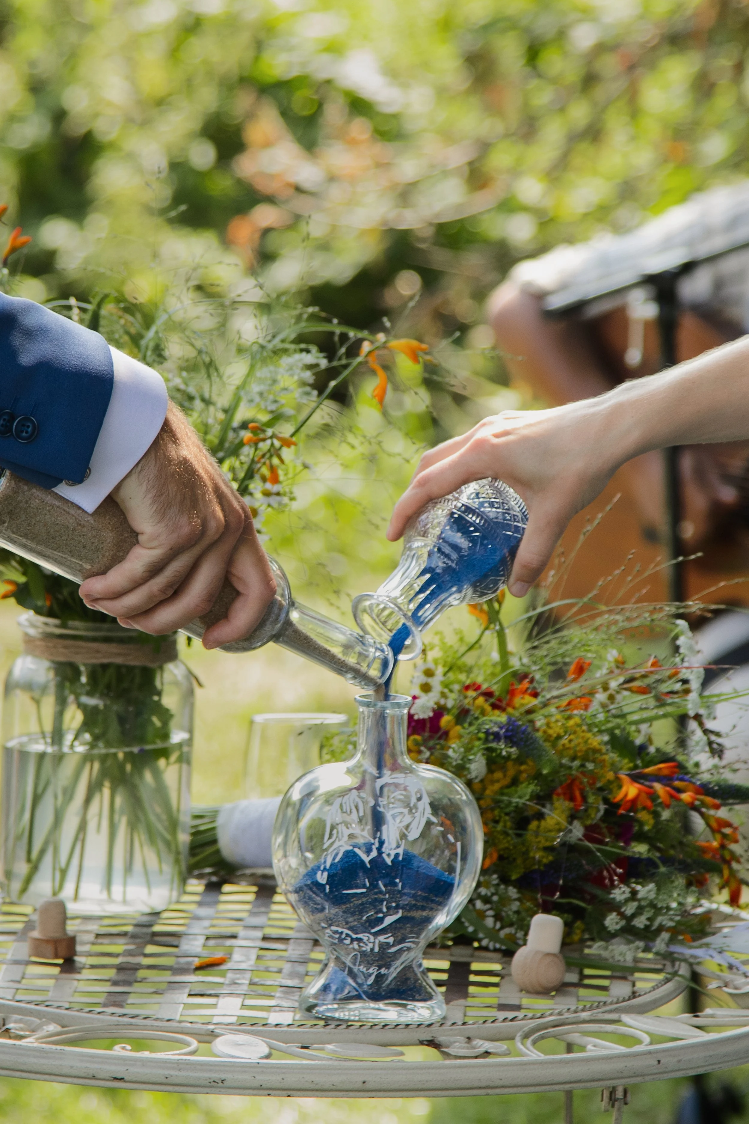 Brautpaar schüttet blaue Flüssigkeit in ein Glas.