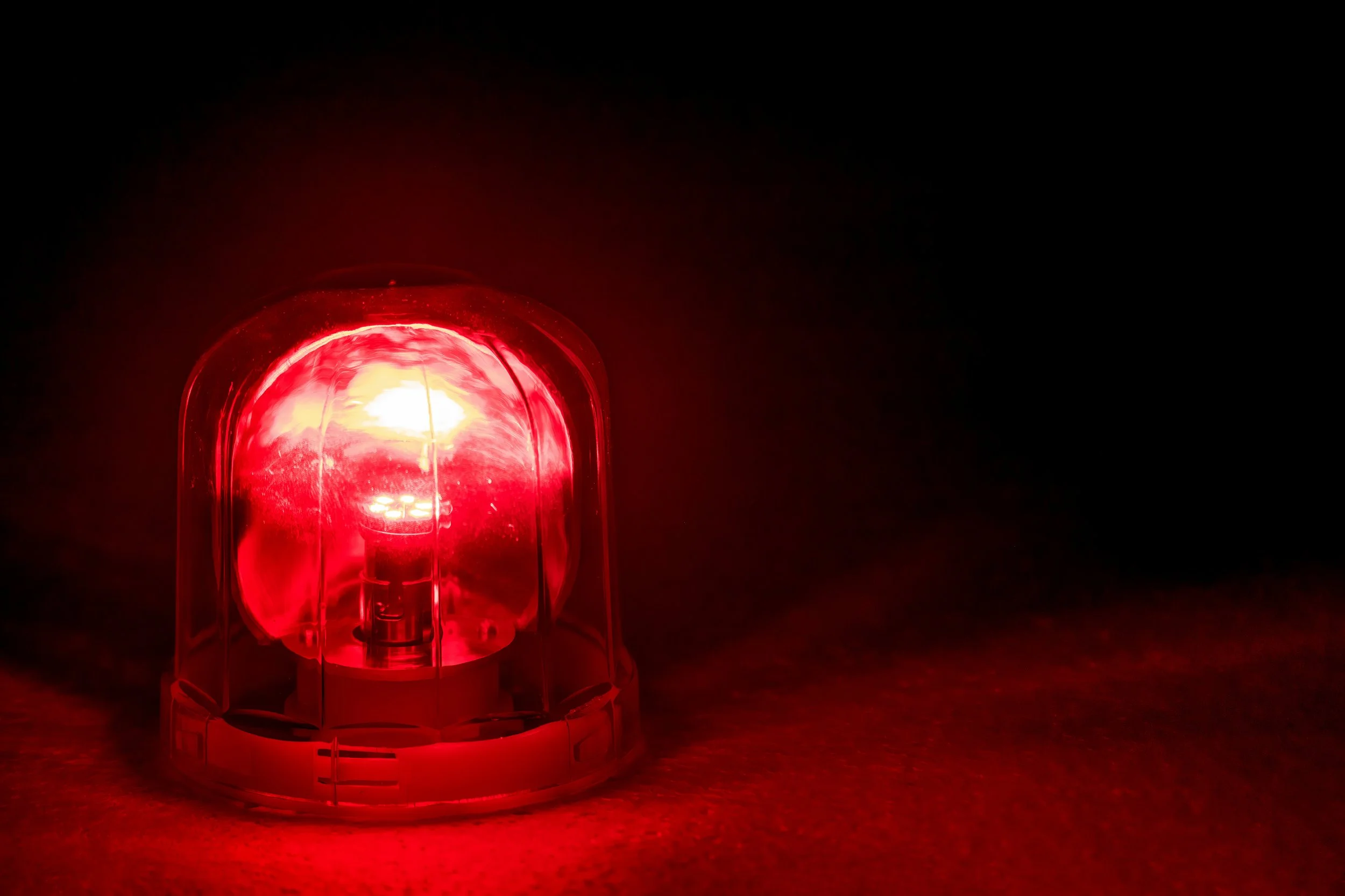 Red flashing emergency warning light with a dark background.