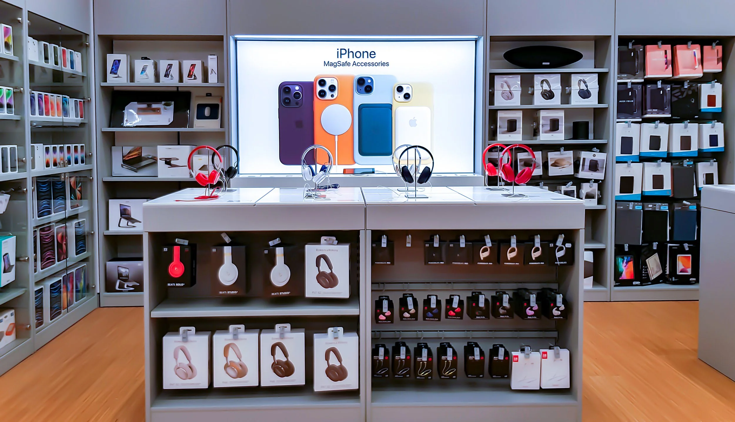 Display of iPhone accessories, including headphones and cases, inside an electronics store.