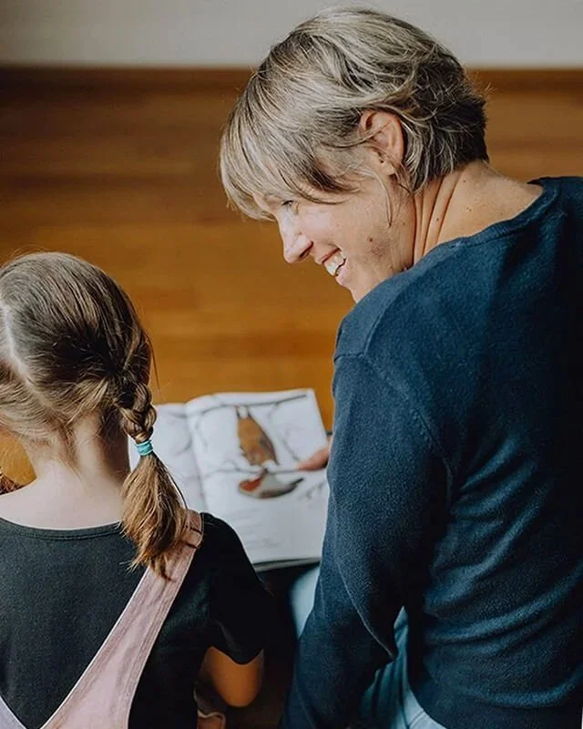 Sara Sommer in Begleitung von Kindern und sie lesen ein Buch sieht sie beide von hinten