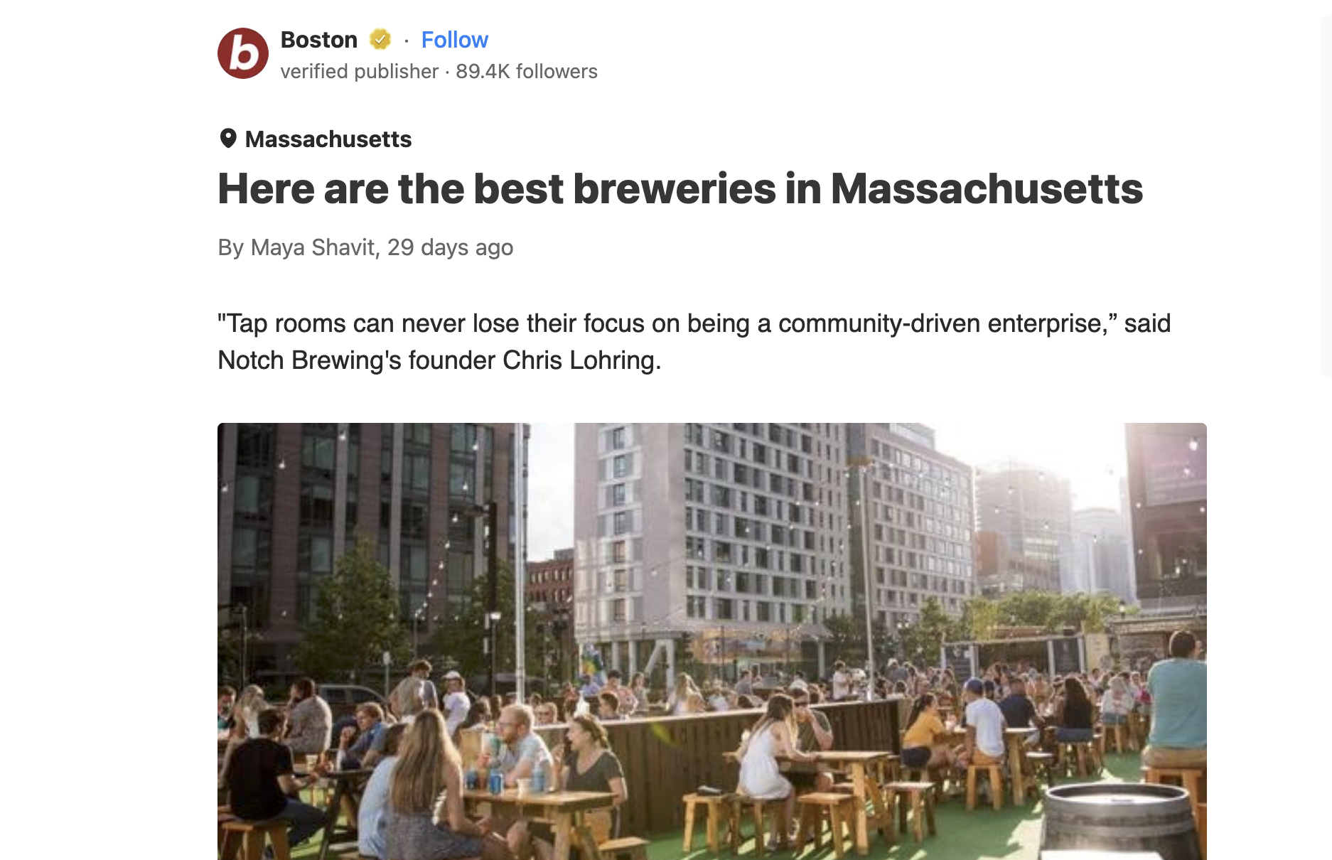People gathering outdoors at a brewery patio in an urban setting with tall buildings in the background.