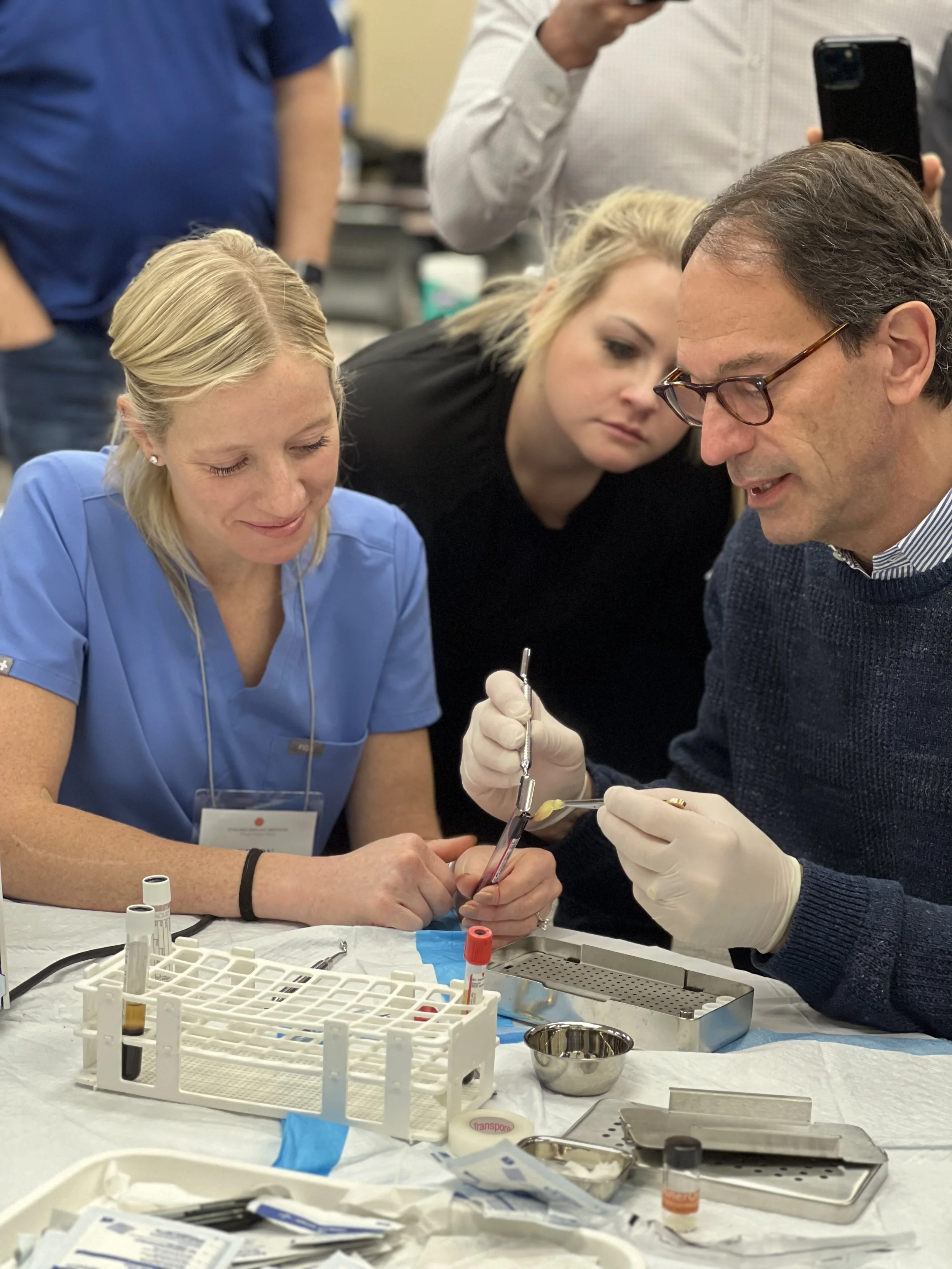 Two women dentists and a man who is also a dentist who is on the faculty. The man is teaching them in an implant dentistry training.