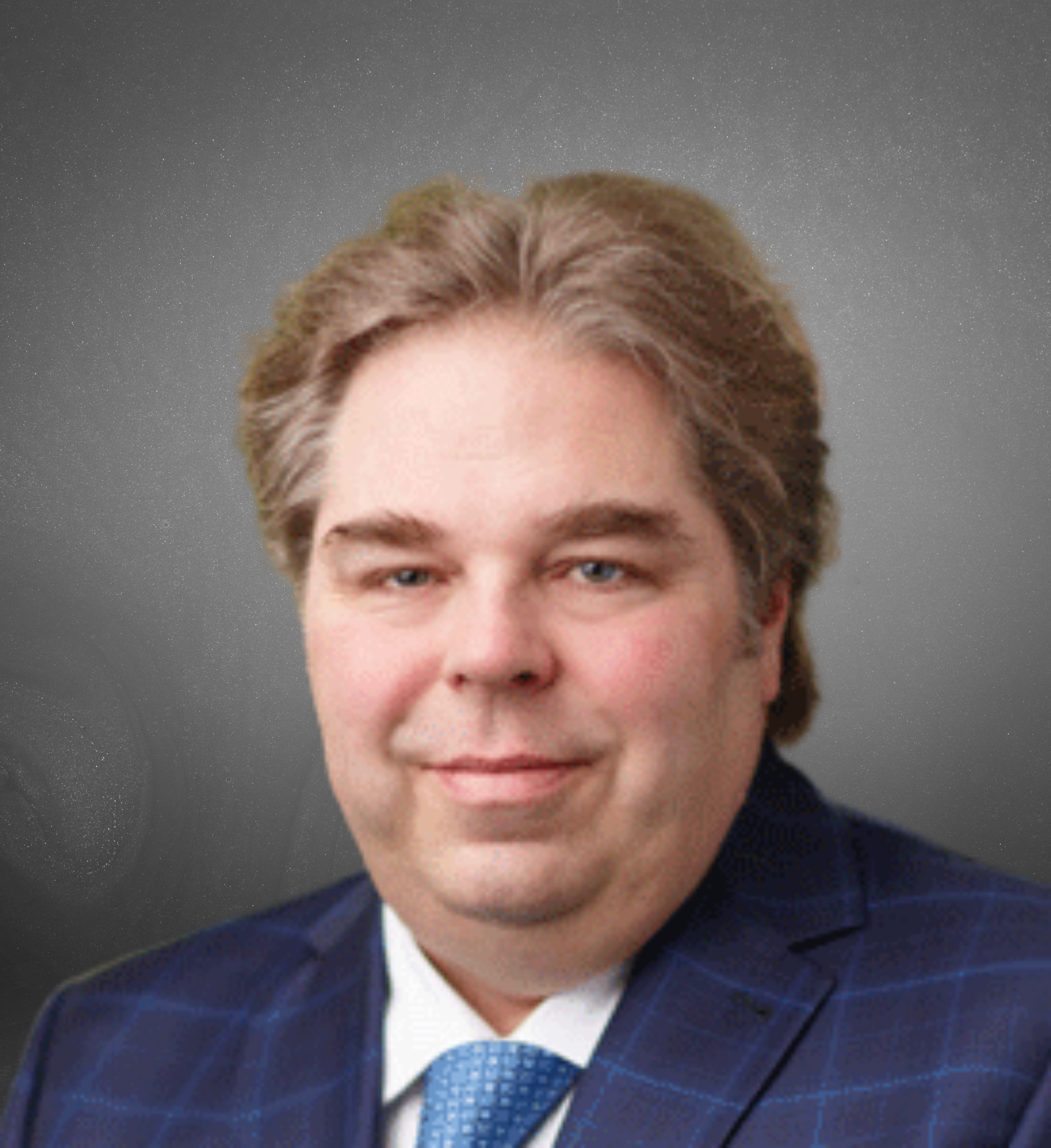 One of our Faculty, a man with light brown hair, wearing a blue checkered suit, white shirt, and blue tie, smiling with a starry night sky background.