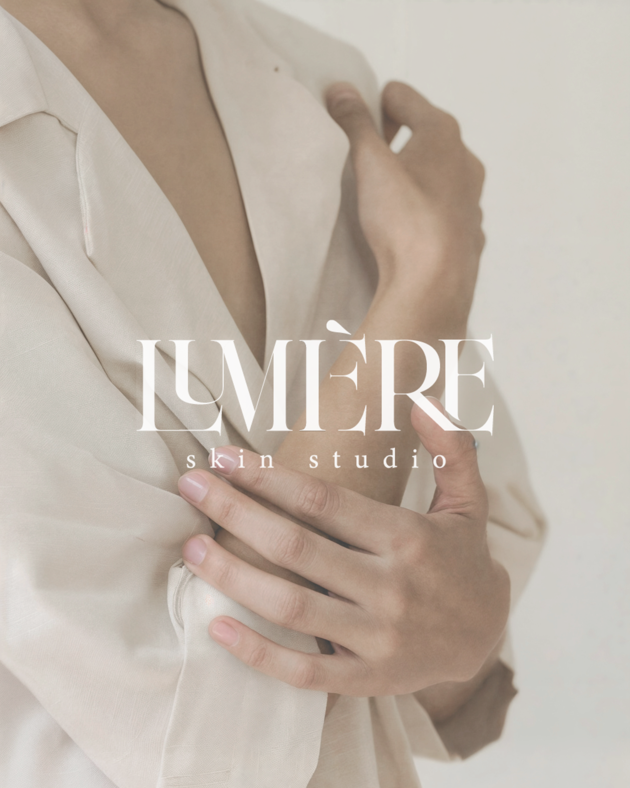 Close-up of a woman in a beige silk shirt touching her shoulder and arm, with text overlay reading "LUMIÈRE skin studio."